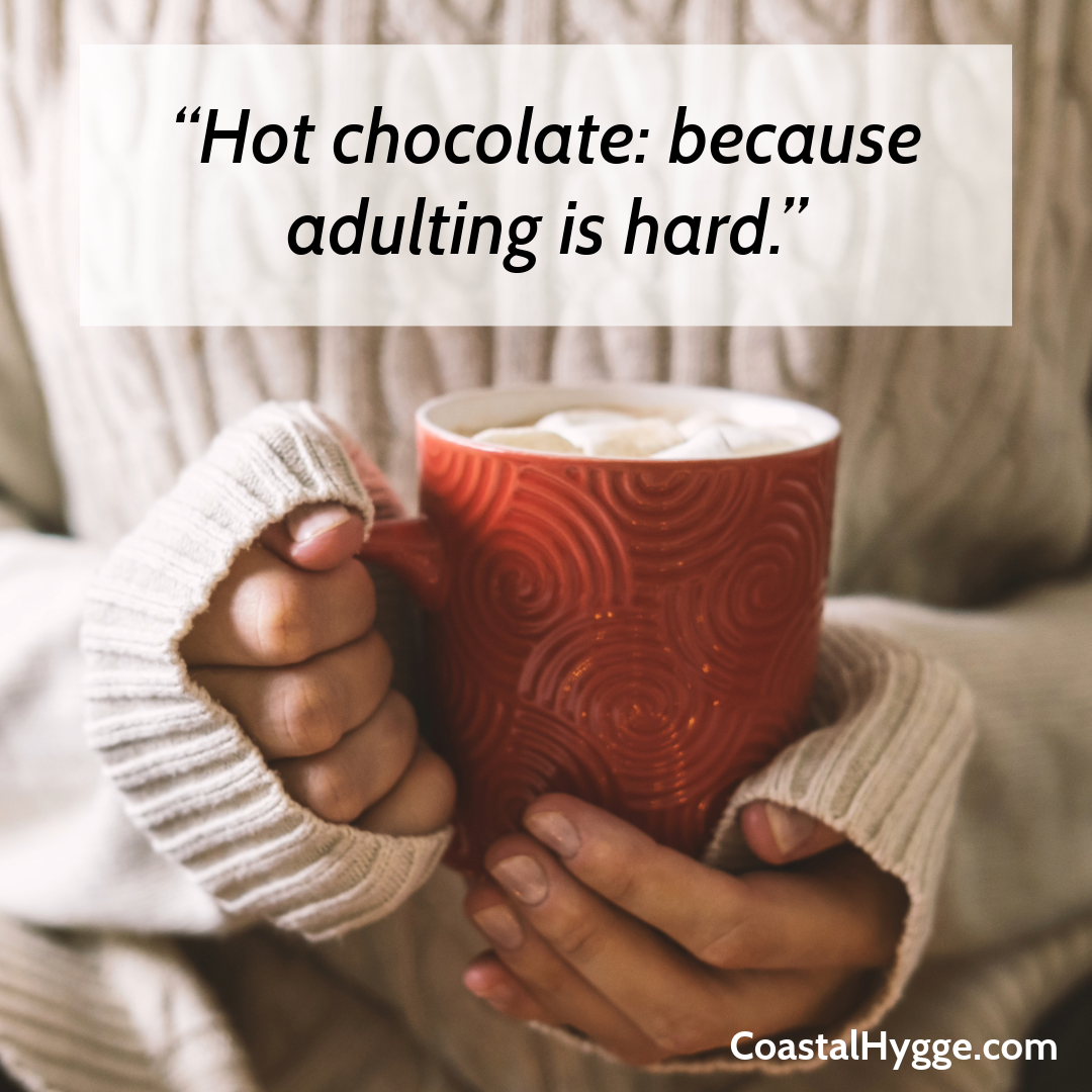 Woman in off-white sweater holding a red cup of hot chocolate. The quote said "Hot chocolate: because adulting is hard."