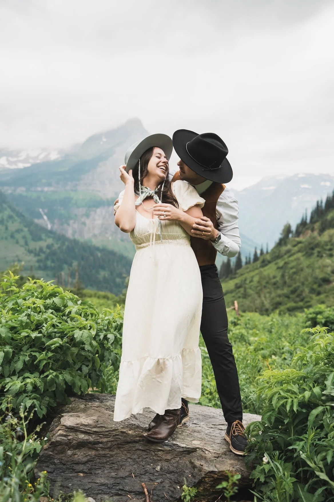 A couple dressed in vintage outdoor clothing sharing a joyful moment in Glacier National Park