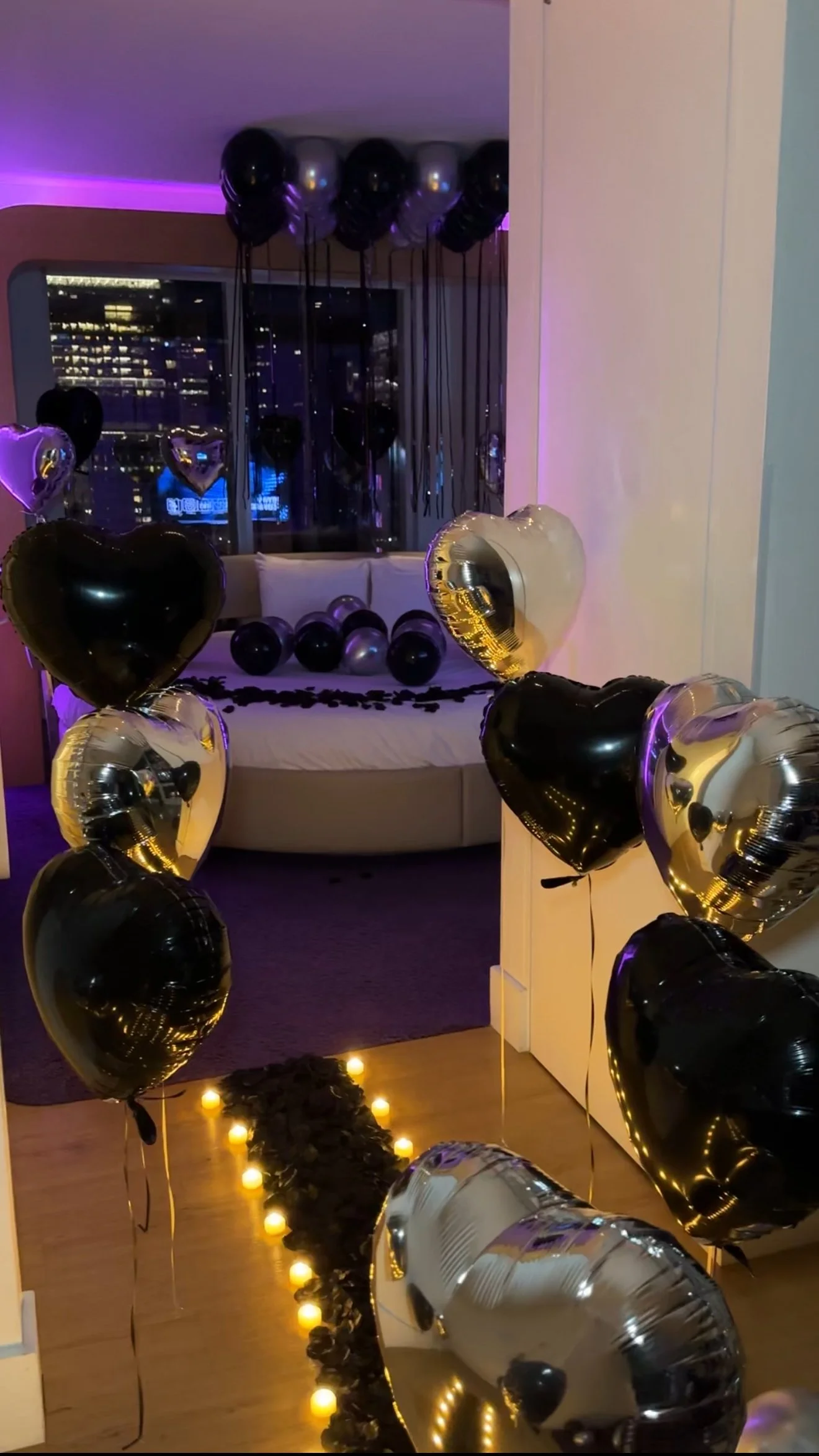 Hotel room decorated with black and silver balloons, 'Happy Birthday' banner, and heart balloons