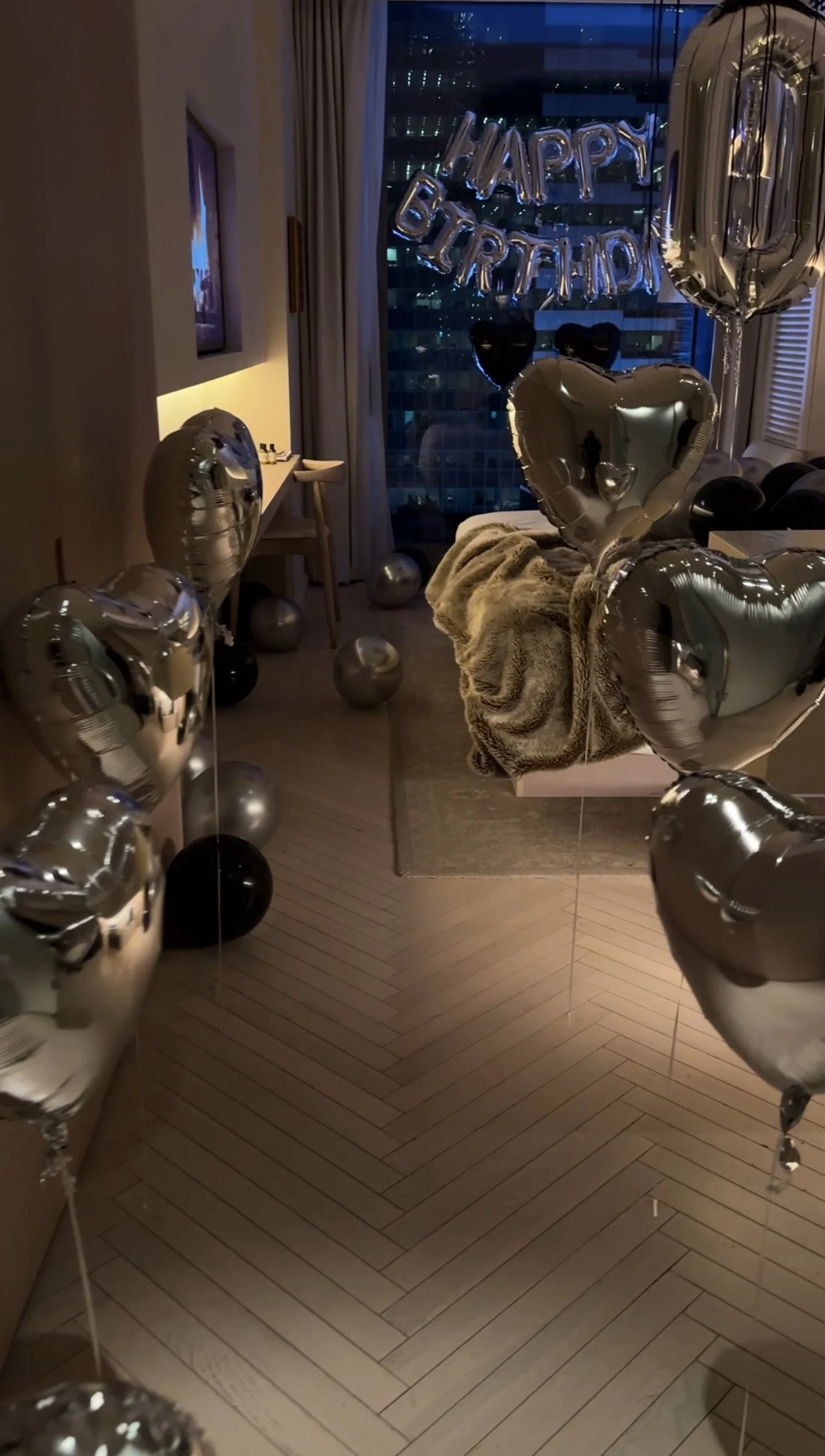 Hotel room decorated with black and silver balloons, and 'Happy Birthday Baby' banner,