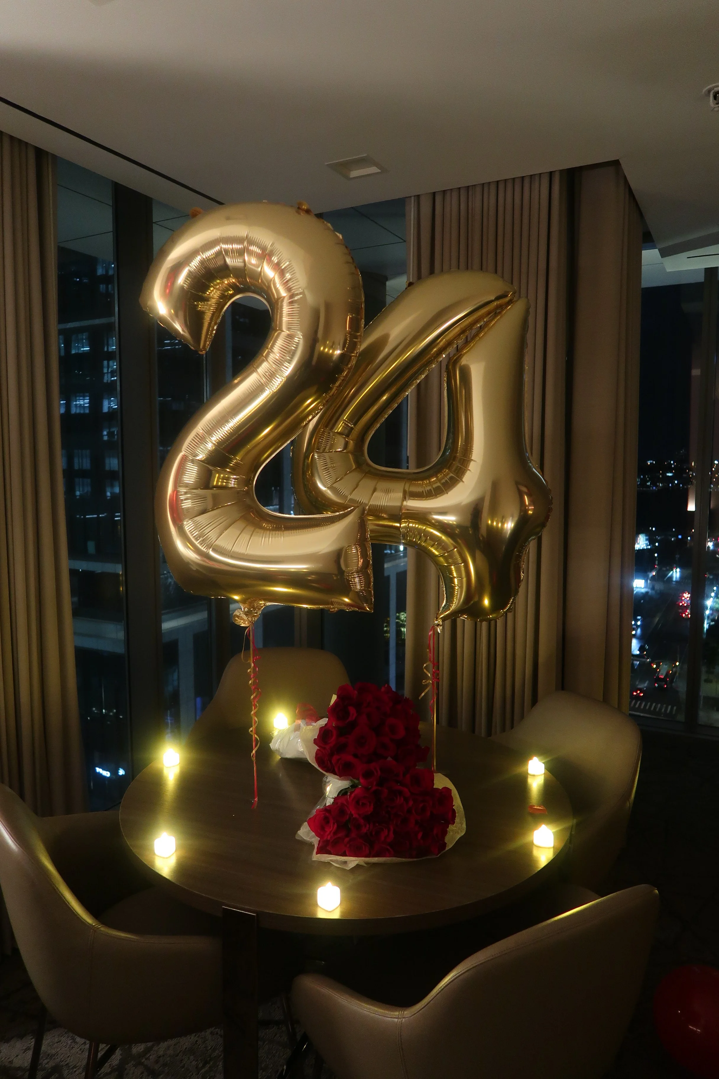 Hotel room decorated large gold '24' balloons, 2 dozen red rose bouquets and heart shaped LED candles