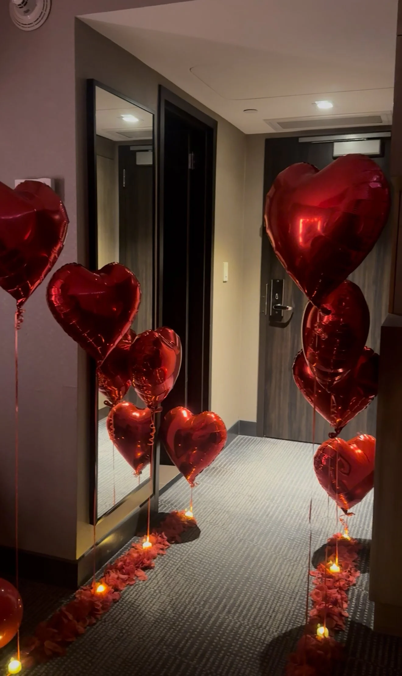 Hotel room decorated with red balloons, LED candles, and red rose petals