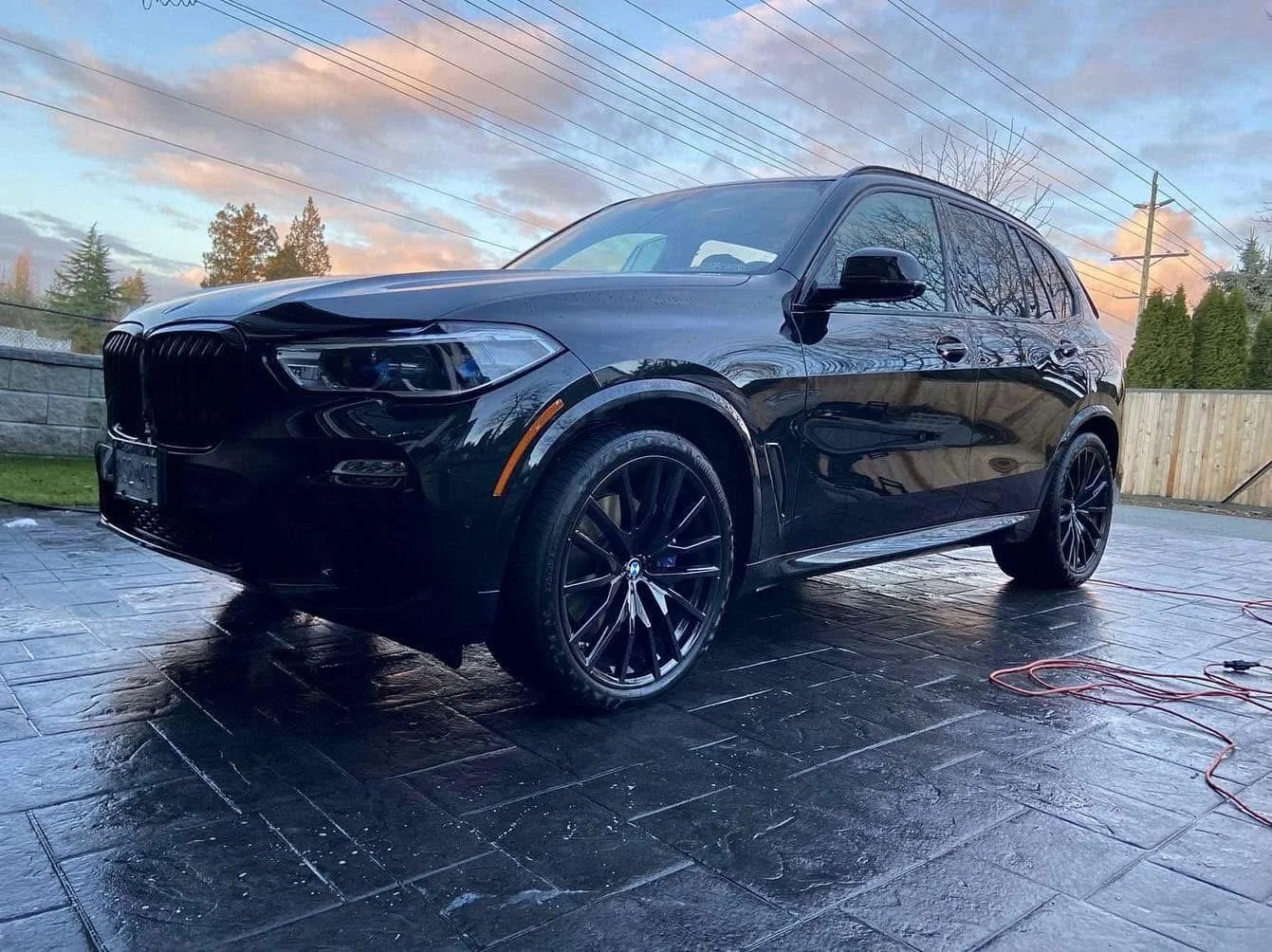 Glossy black BMW SUV with paint correction and wheel detailing
