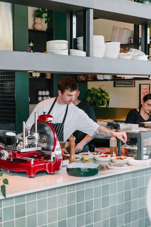 A chef preparing food in a restaurant kitchen with plates and kitchen tools around him.