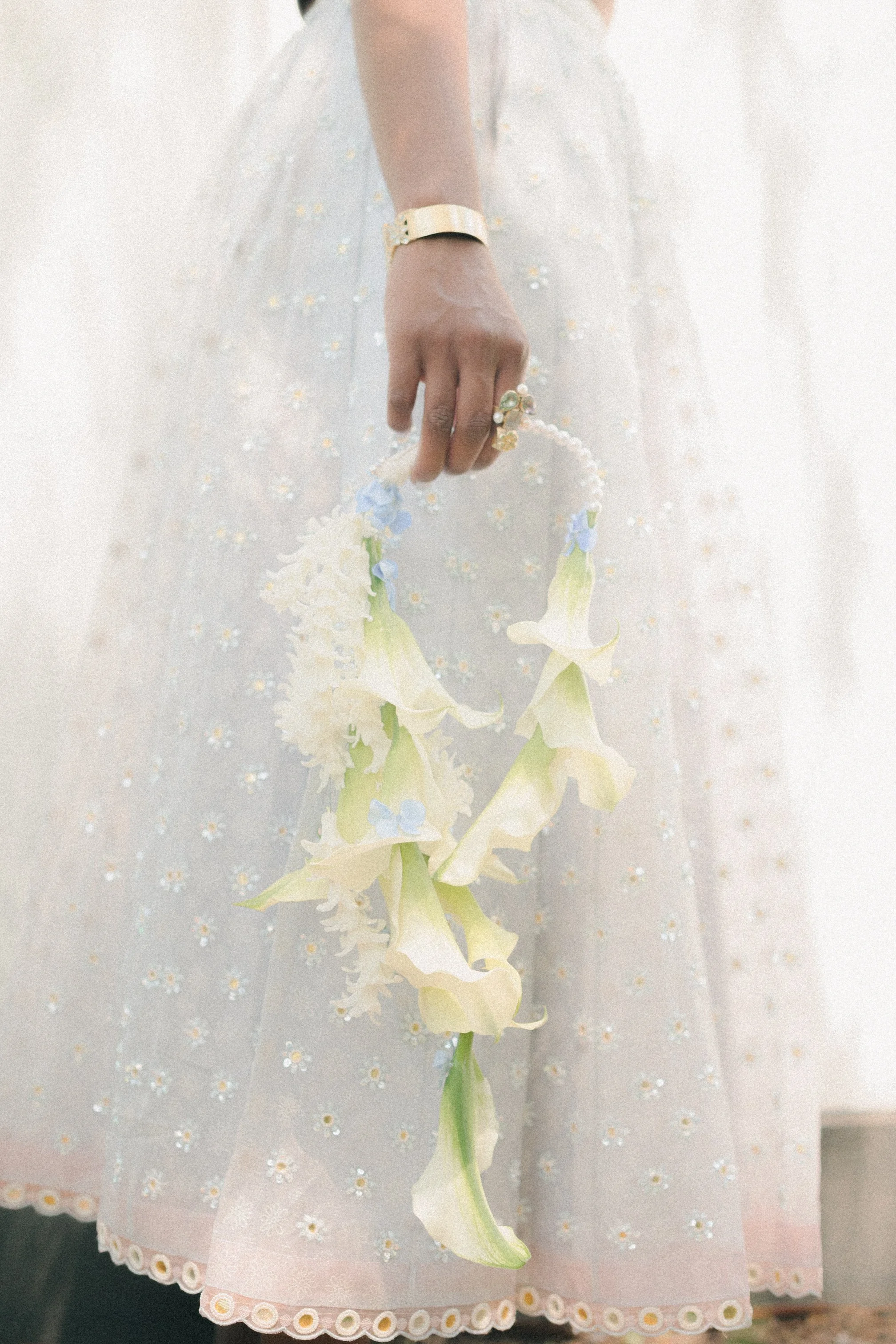 People celebrating outdoors, holding and releasing colored smoke bombs that emit green, yellow, and blue smoke, with a building and trees in the background.