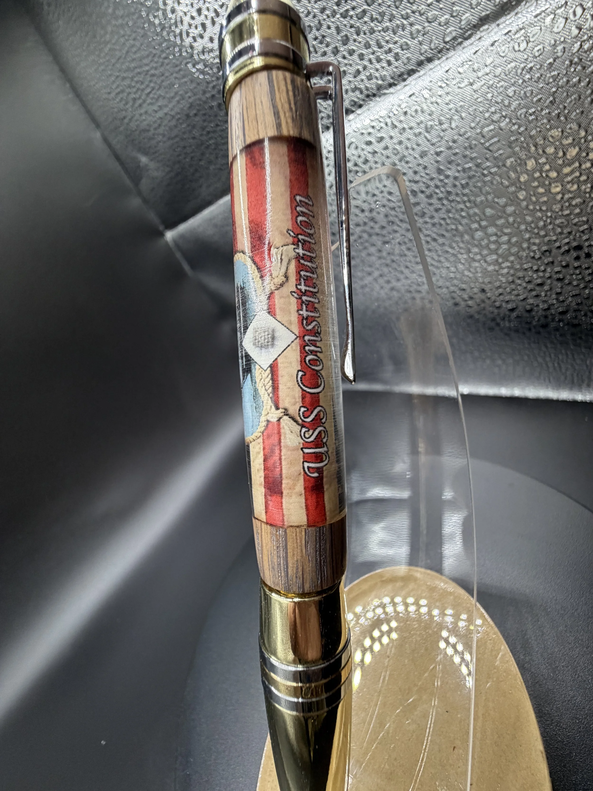 Close-up of a bamboo handle on a bamboo fishing rod with a clip, held above a pool table with a penny and gold coins.