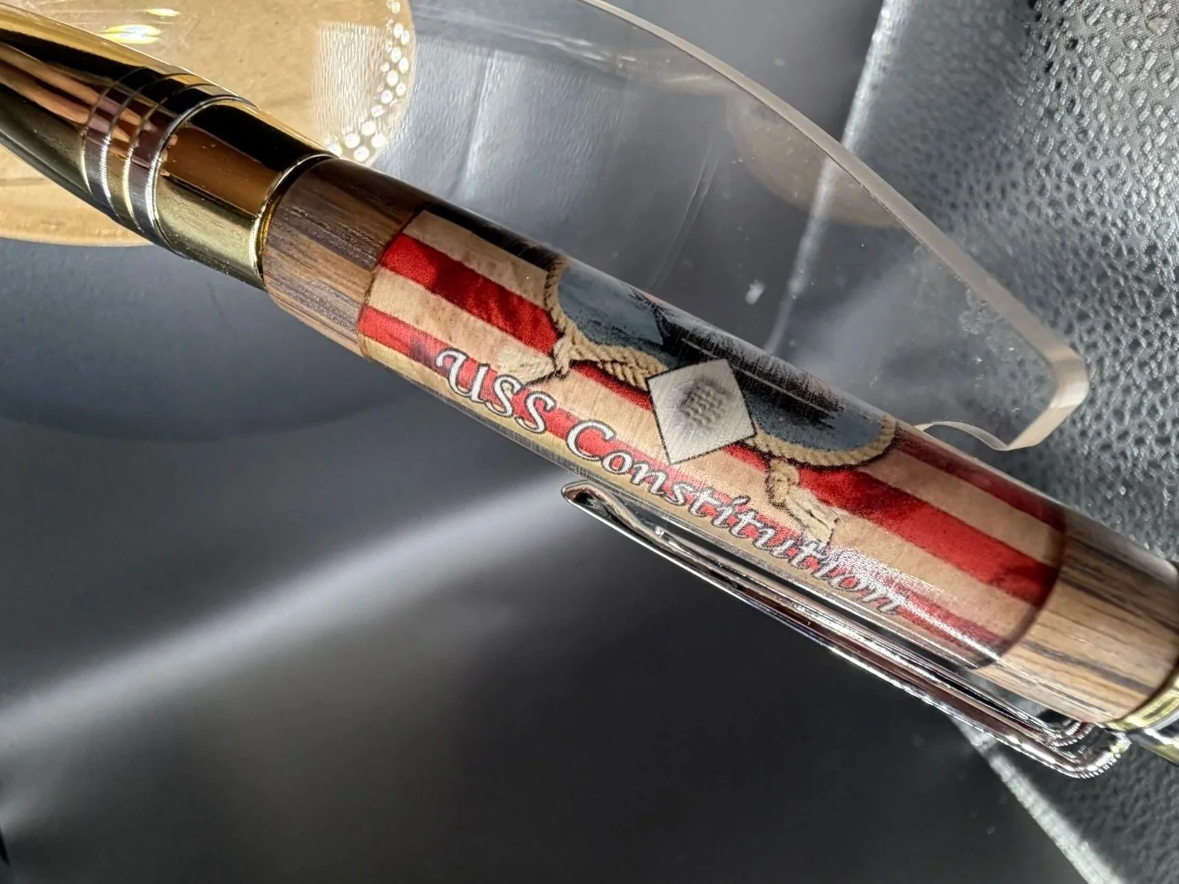 Close-up of a wooden-handled fishing rod with an American flag sticker and the words "Hannah Constellation" on it, placed inside a metallic sink.