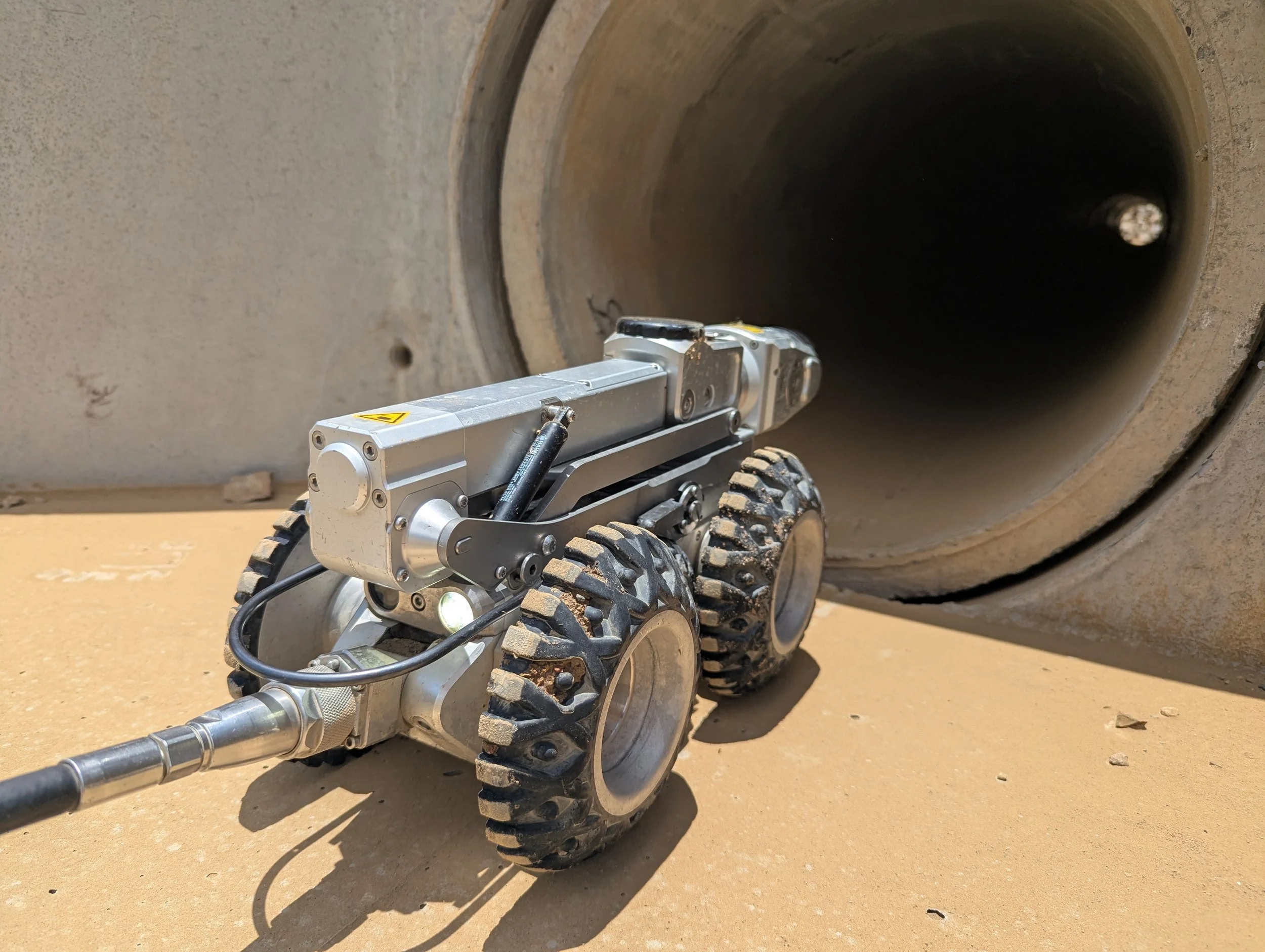 Robotic CCTV crawler entering a large stormwater pipeline during a mainline drainage inspection for civil infrastructure condition assessment, sewer and stormwater asset inspections, and WinCan reporting.
