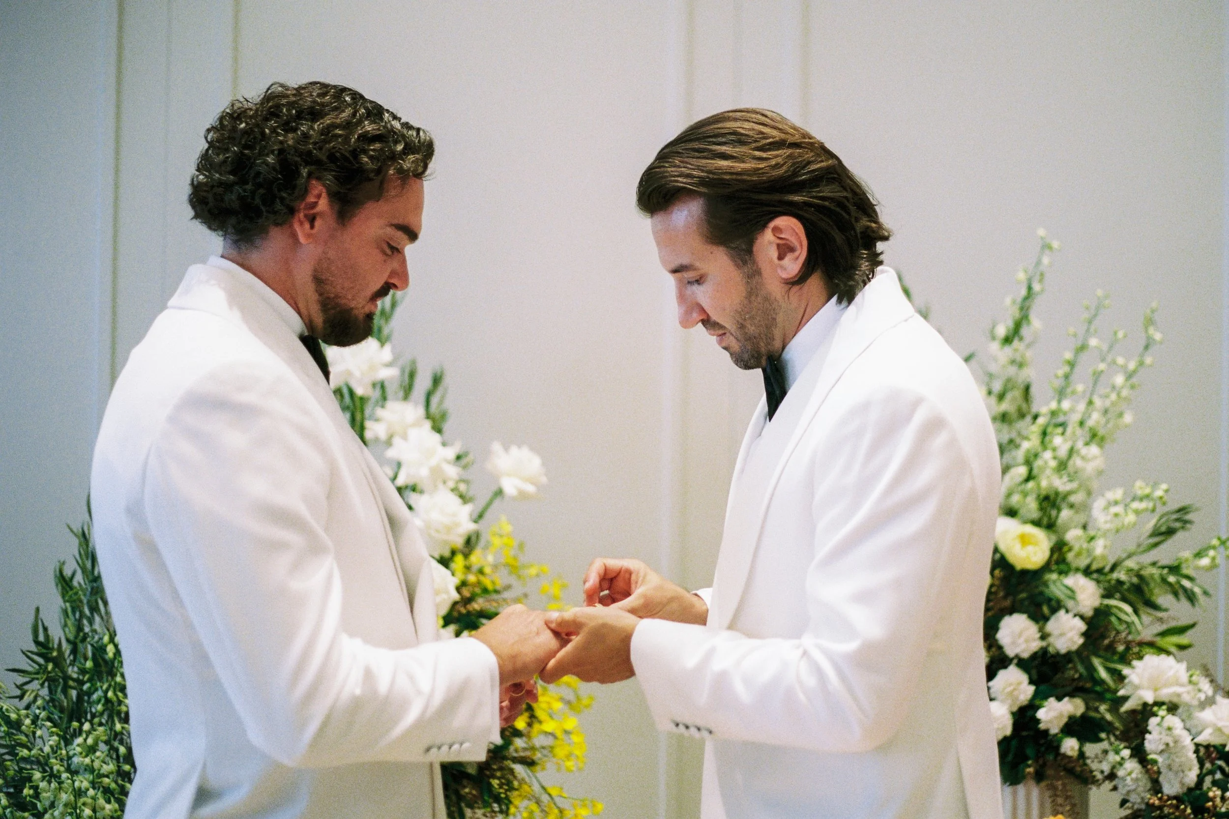Two grooms exchanging rings at InterContinental Sorrento, framed by Poppy Culture’s white and yellow floral arrangements.