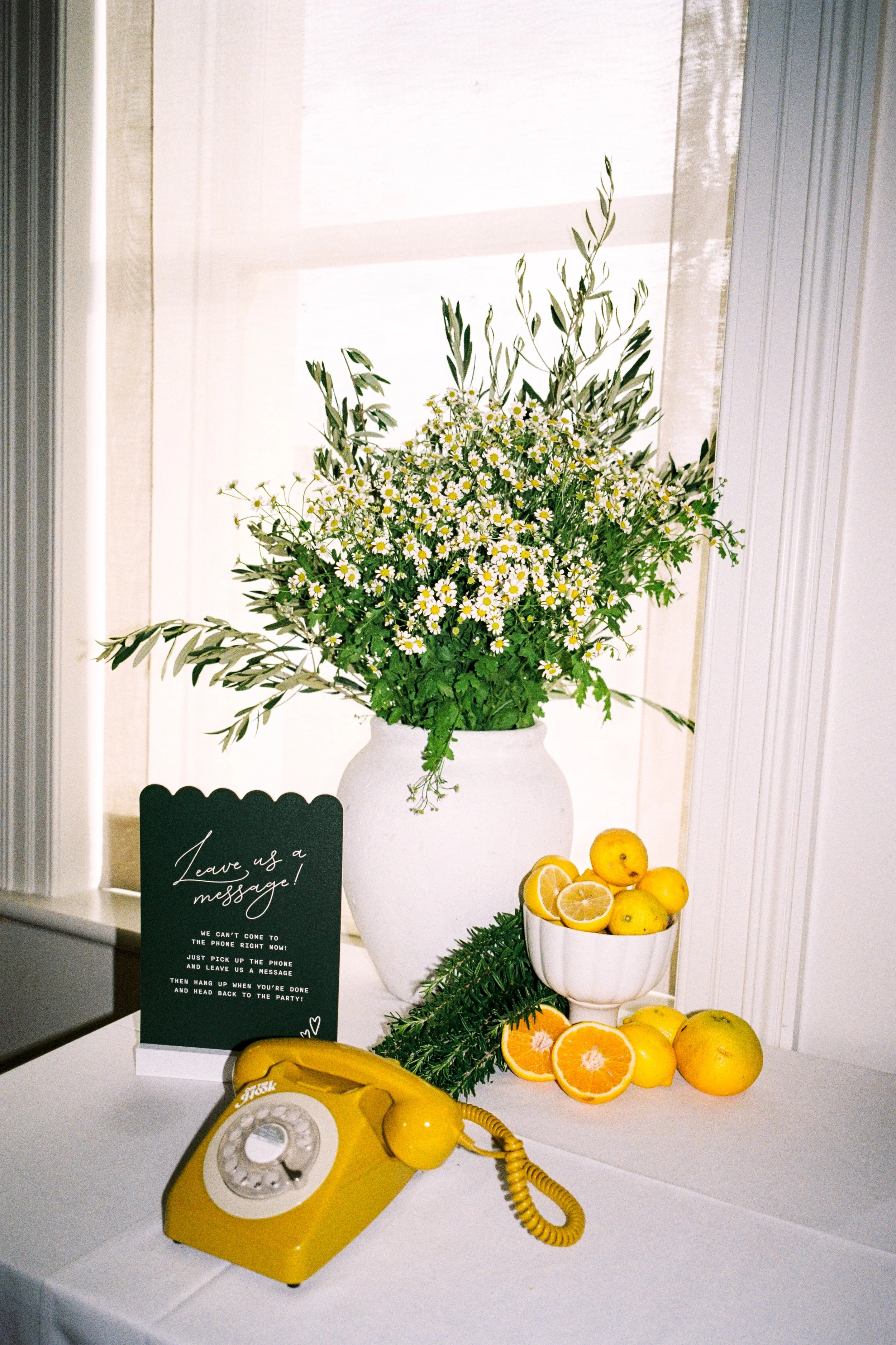 Citrus‑themed message station at InterContinental Sorrento styled by Poppy Culture with white florals, lemons and a vintage yellow phone.