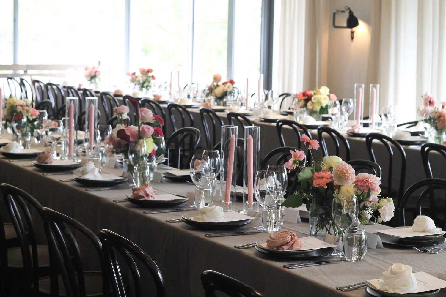Polperro wedding tablescape with soft pink and peach floral centrepieces and modern candle styling.