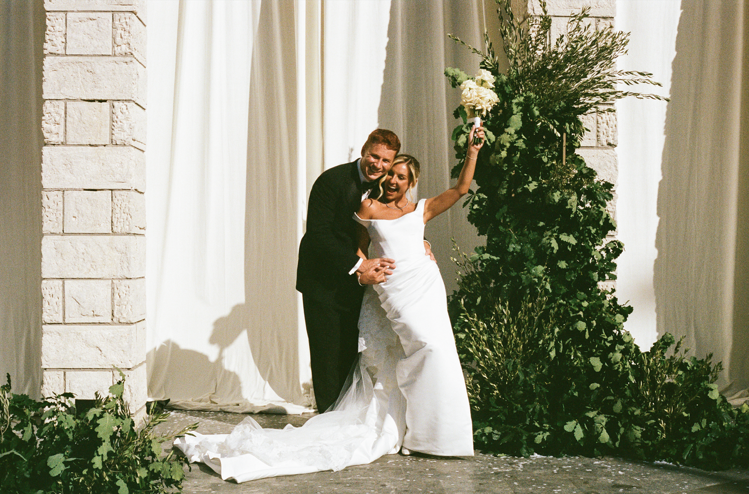 Greek Orthodox Church Red Hill wedding exit with the bride holding a Poppy Culture bouquet and white drapery framing the entrance.