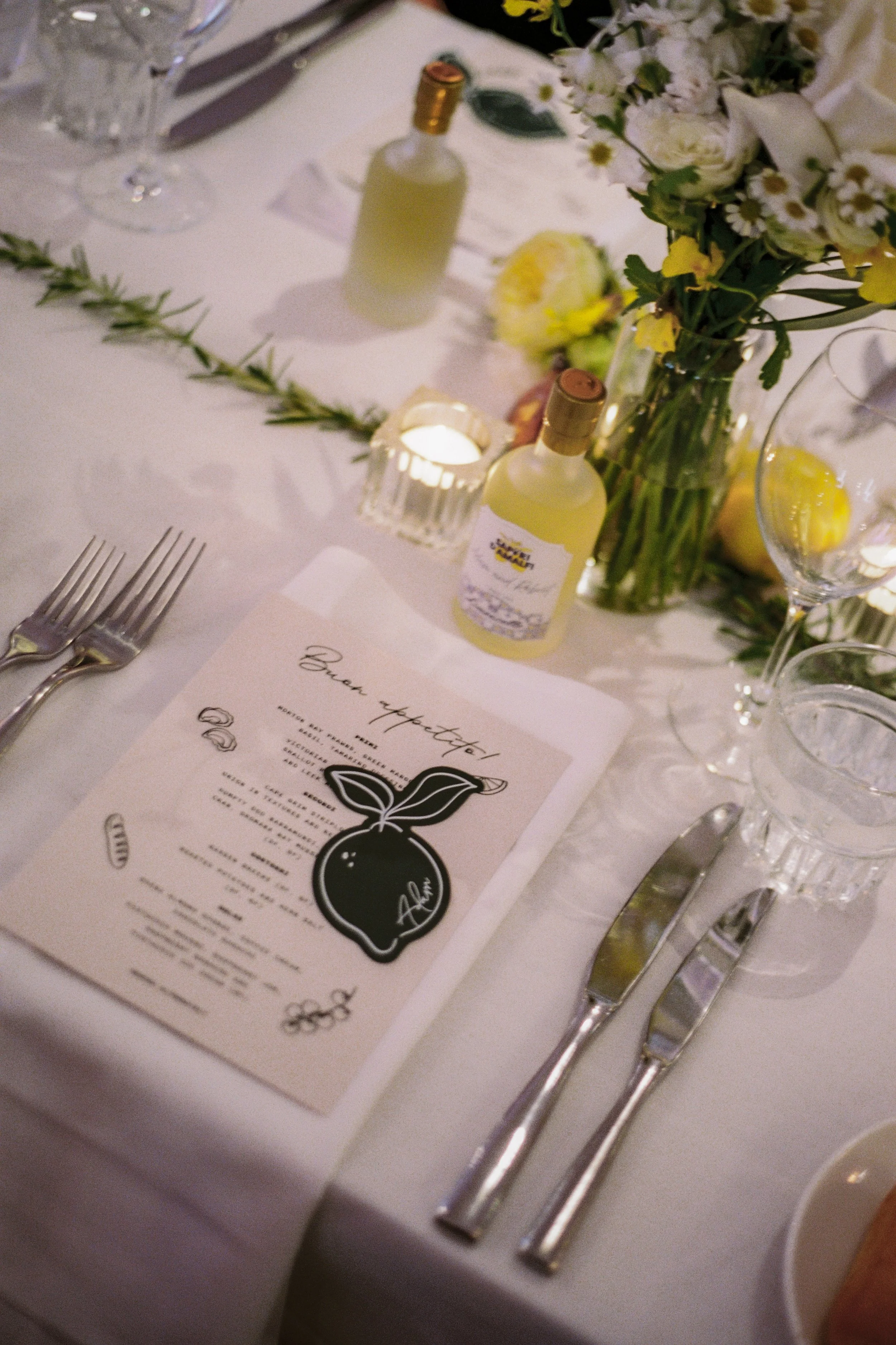 Lemon‑themed place setting at InterContinental Sorrento with Poppy Culture’s refined florals, and menu card and miniature limoncello bottle.