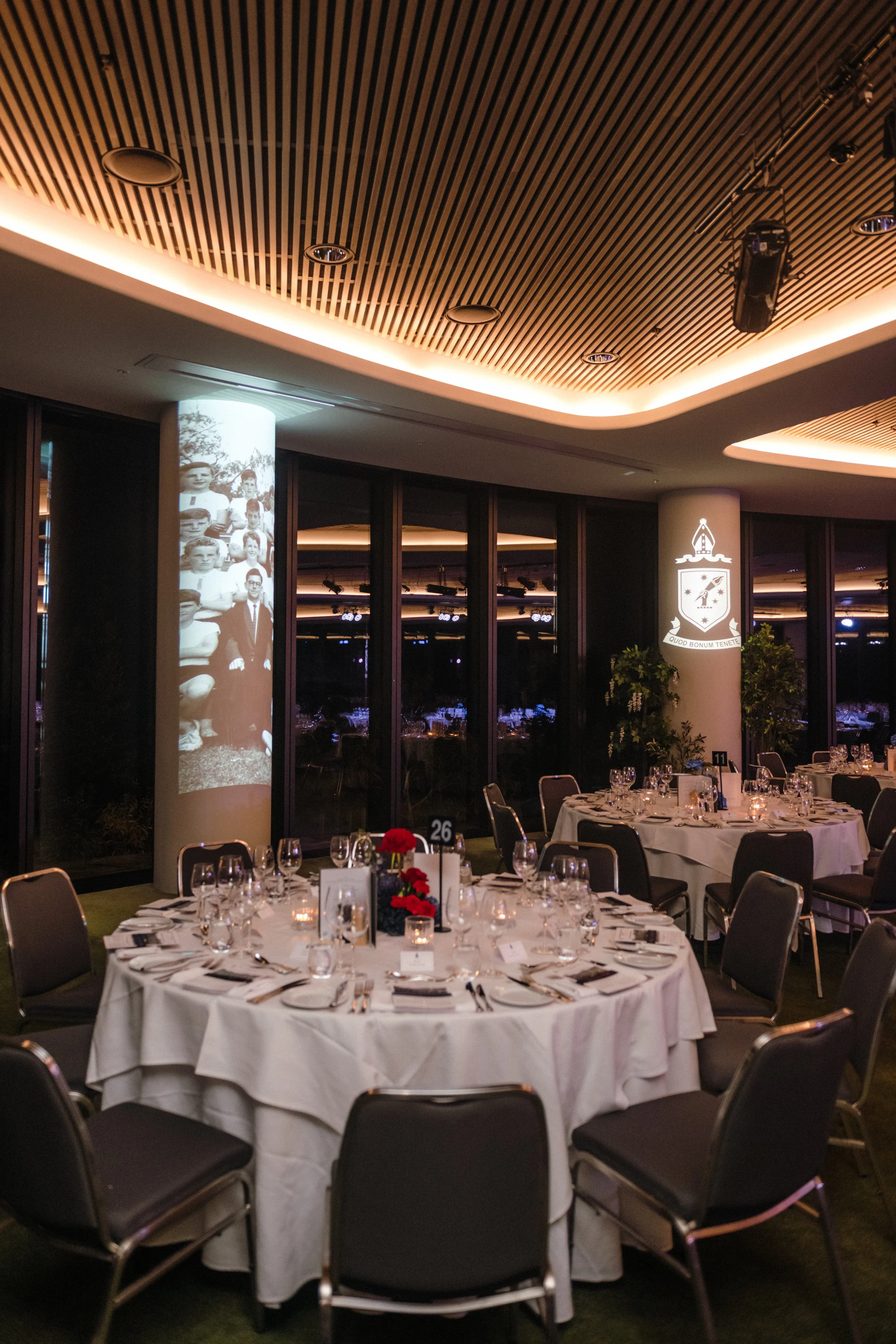 Modern‑lux corporate event styling by Poppy Culture at RACV Cape Schanck Resort, featuring an elegant dining room with round tables dressed in white linens, refined glassware and structured place settings. Blue‑toned floral centrepieces and numbered 