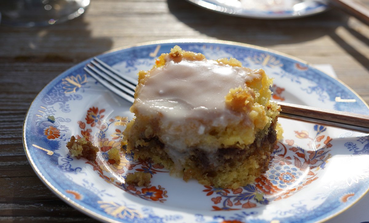 A slice of iced coffee cake on a decorative blue and orange plate with a fork.