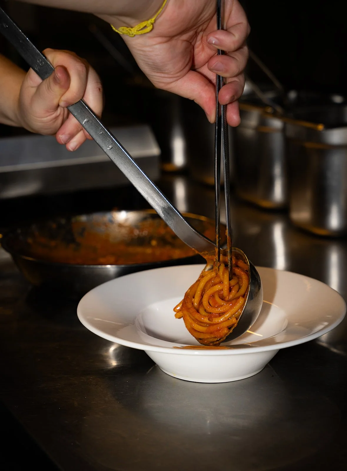 Spaghetti i tomatsauce anrettes med tang i en hvid tallerken hos Il Mattarello