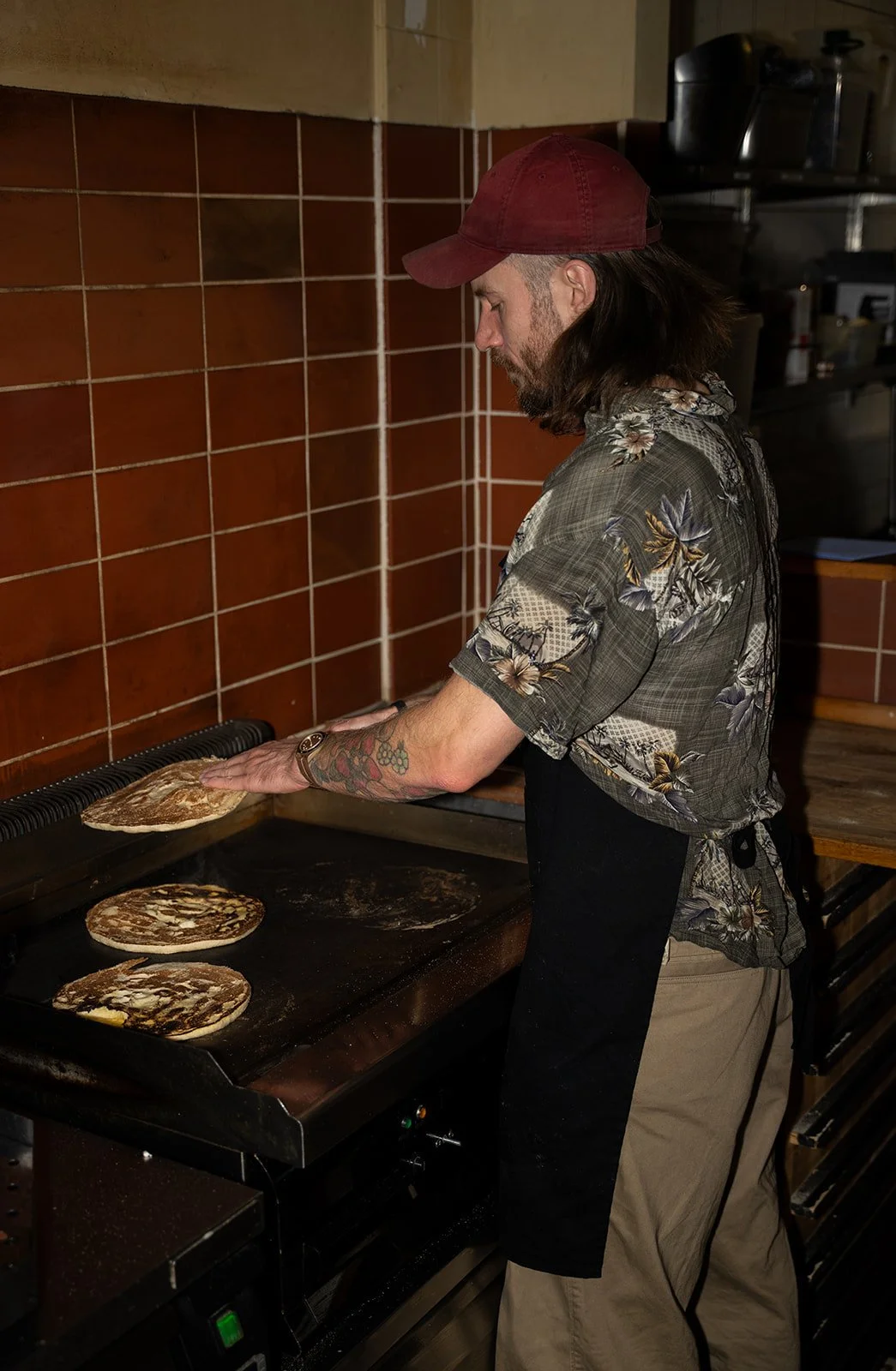 Kok bager fladbrød på stegepladen foran de brune fliser hos Killer Kebab