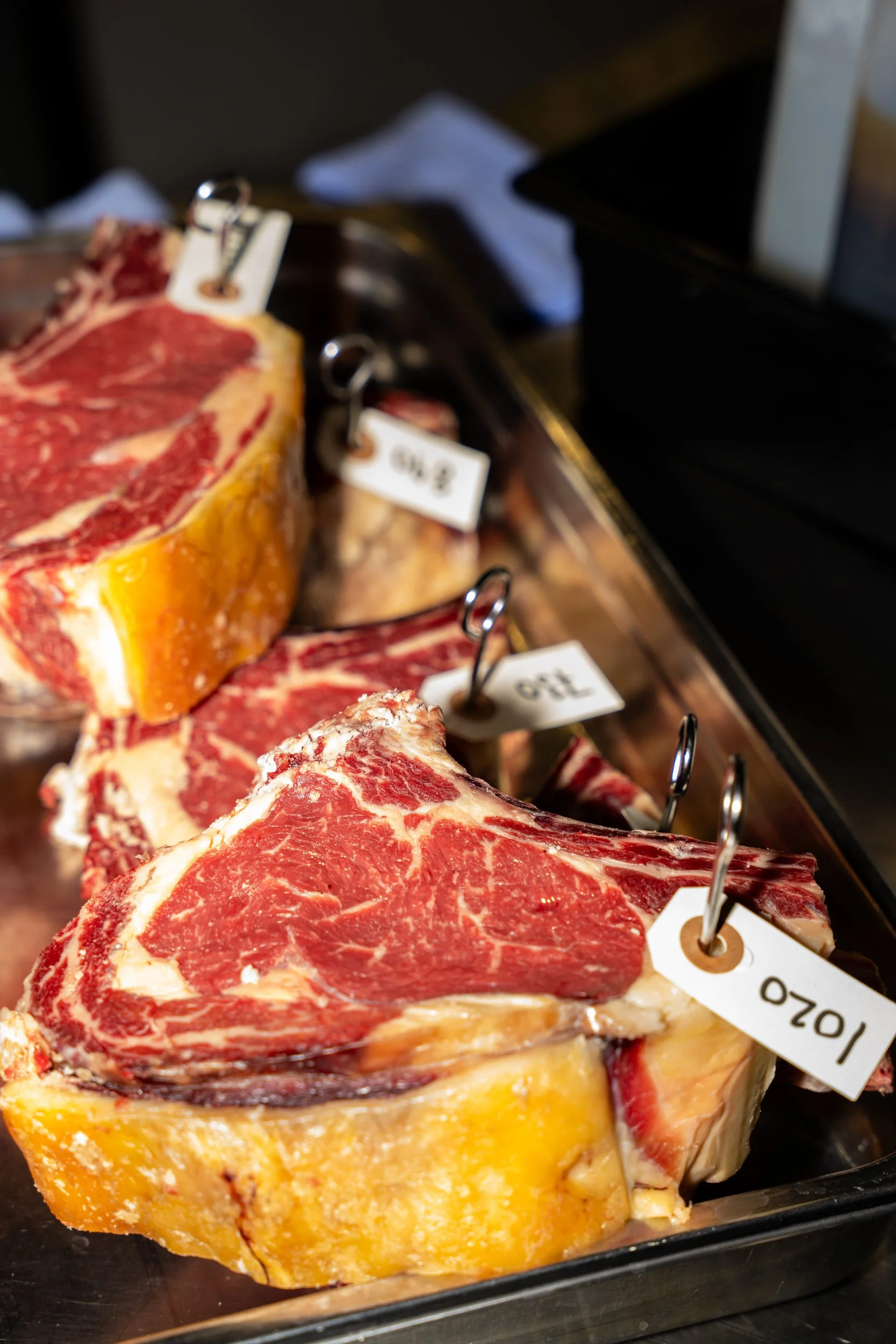 Dry-aged oksekød med mærkesedler på en bakke i køkkenet hos A Hereford Beefstouw