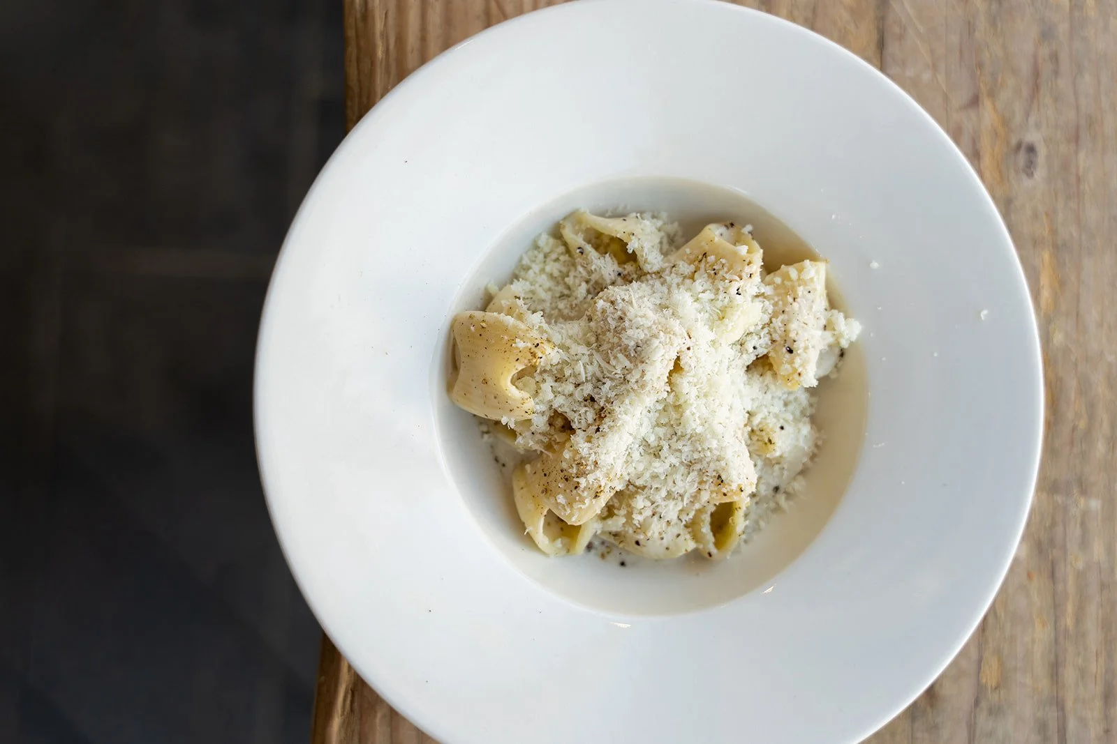 Tallerken med pasta og revet pecorino set ovenfra på et træbord hos Il Mattarello