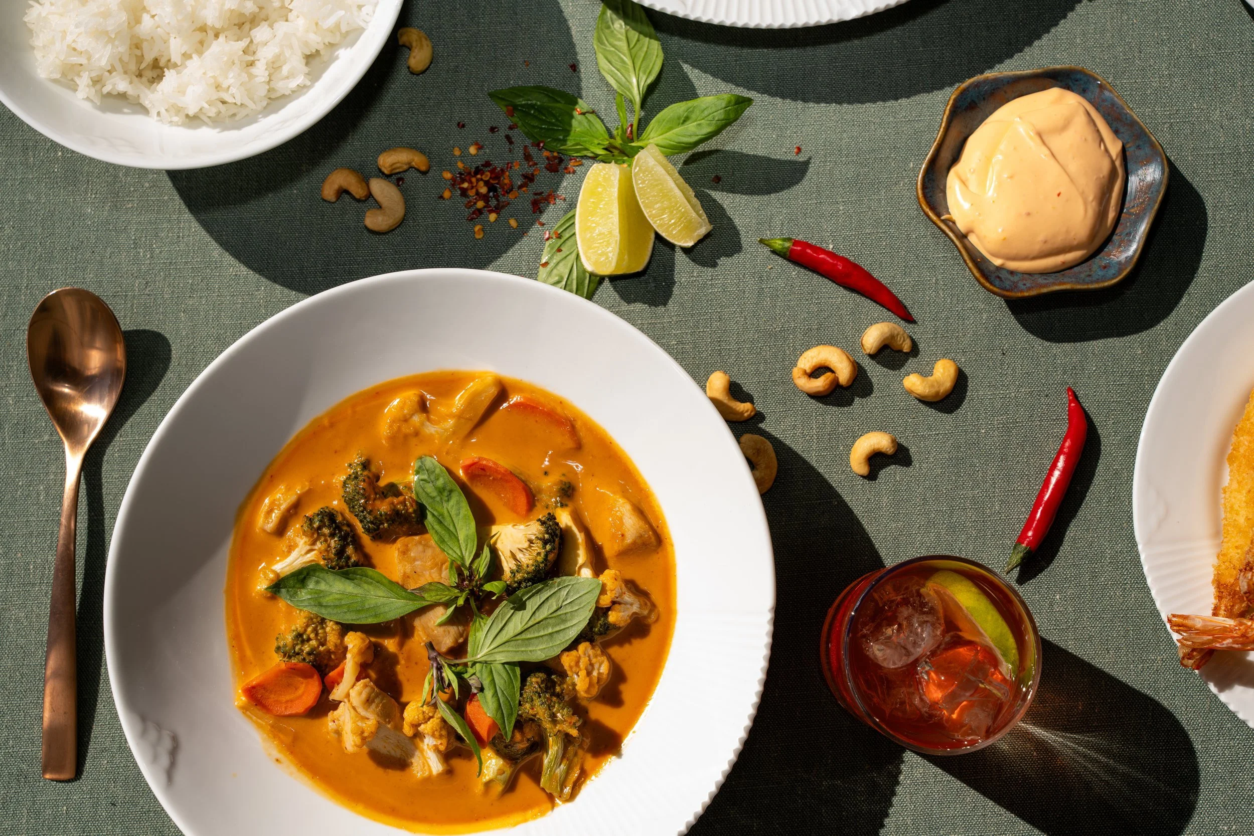 Flat lay of Thai red curry with basil and chili on a green table at WOK Copenhagen – food photographer Copenhagen