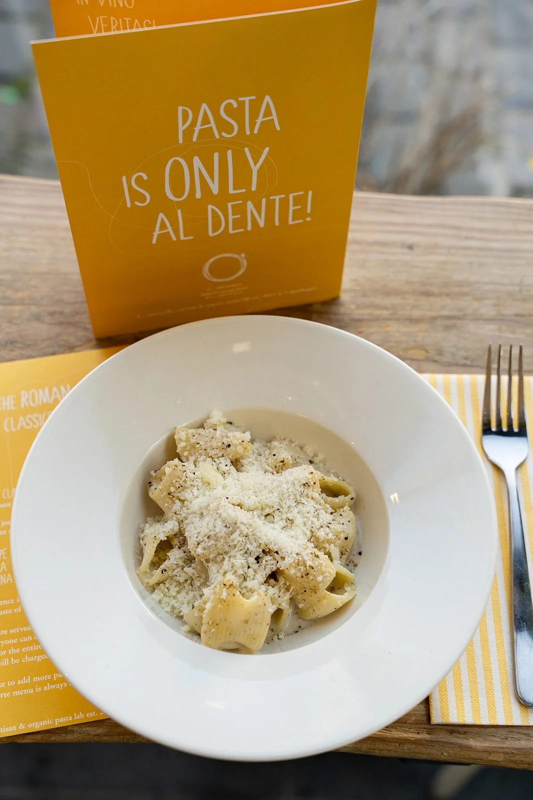 Cacio e pepe foran et gult skilt med teksten Pasta is only al dente hos Il Mattarello
