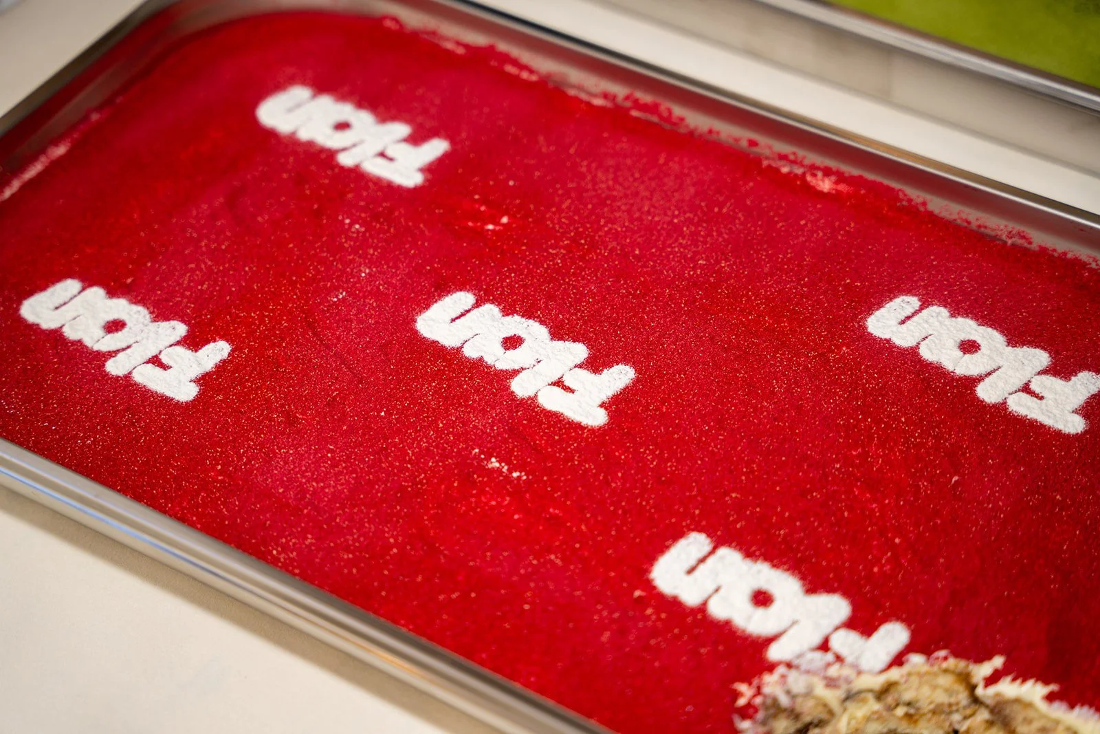 Bakke med tiramisu dækket af rødt drys med Flan-logoet sigtet hen over toppen