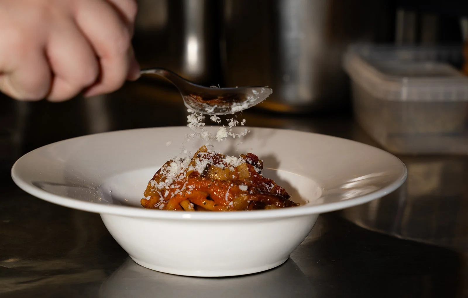 Pecorino rives over en tallerken pasta med tomatsauce i køkkenet hos Il Mattarello