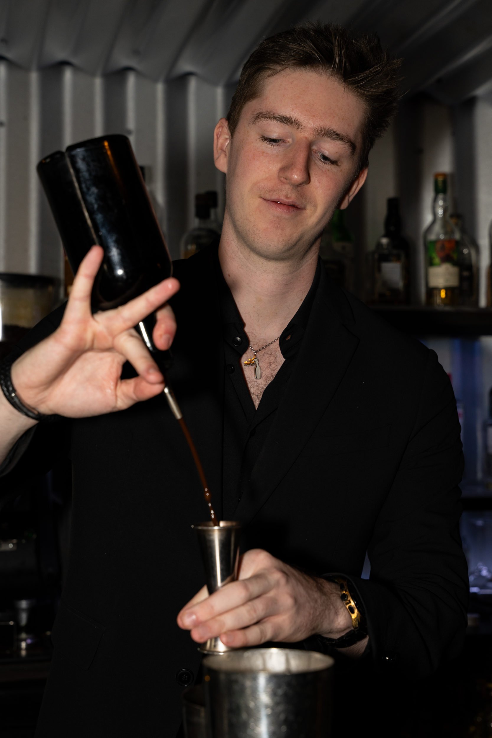 Bartender hælder spiritus i et målebæger over shakeren på Little Green Door København