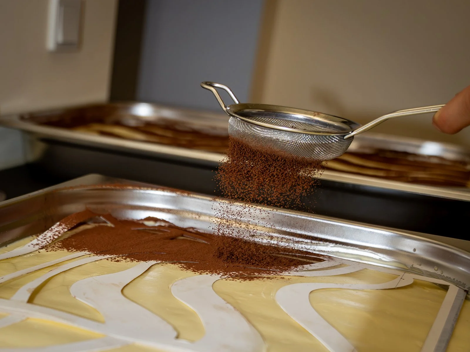 Kakao sigtes ud over bakker med tiramisu i køkkenet før eventet hos Arturel