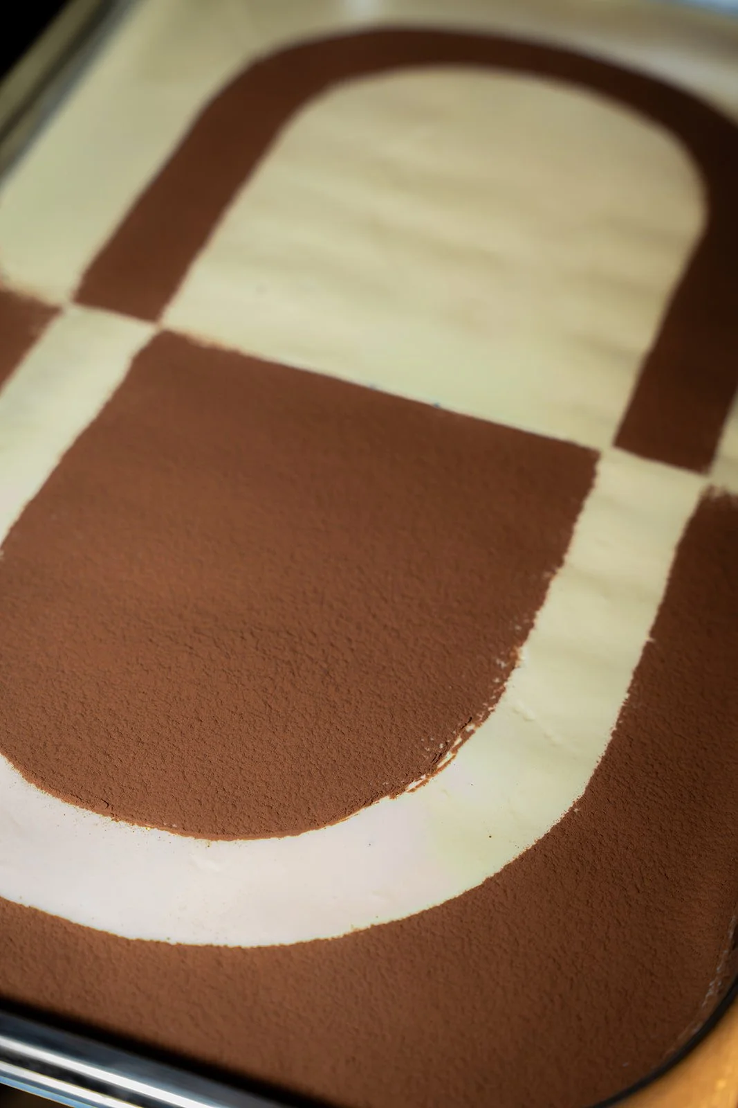 Nærbillede af tiramisu med et grafisk mønster i kakao og creme