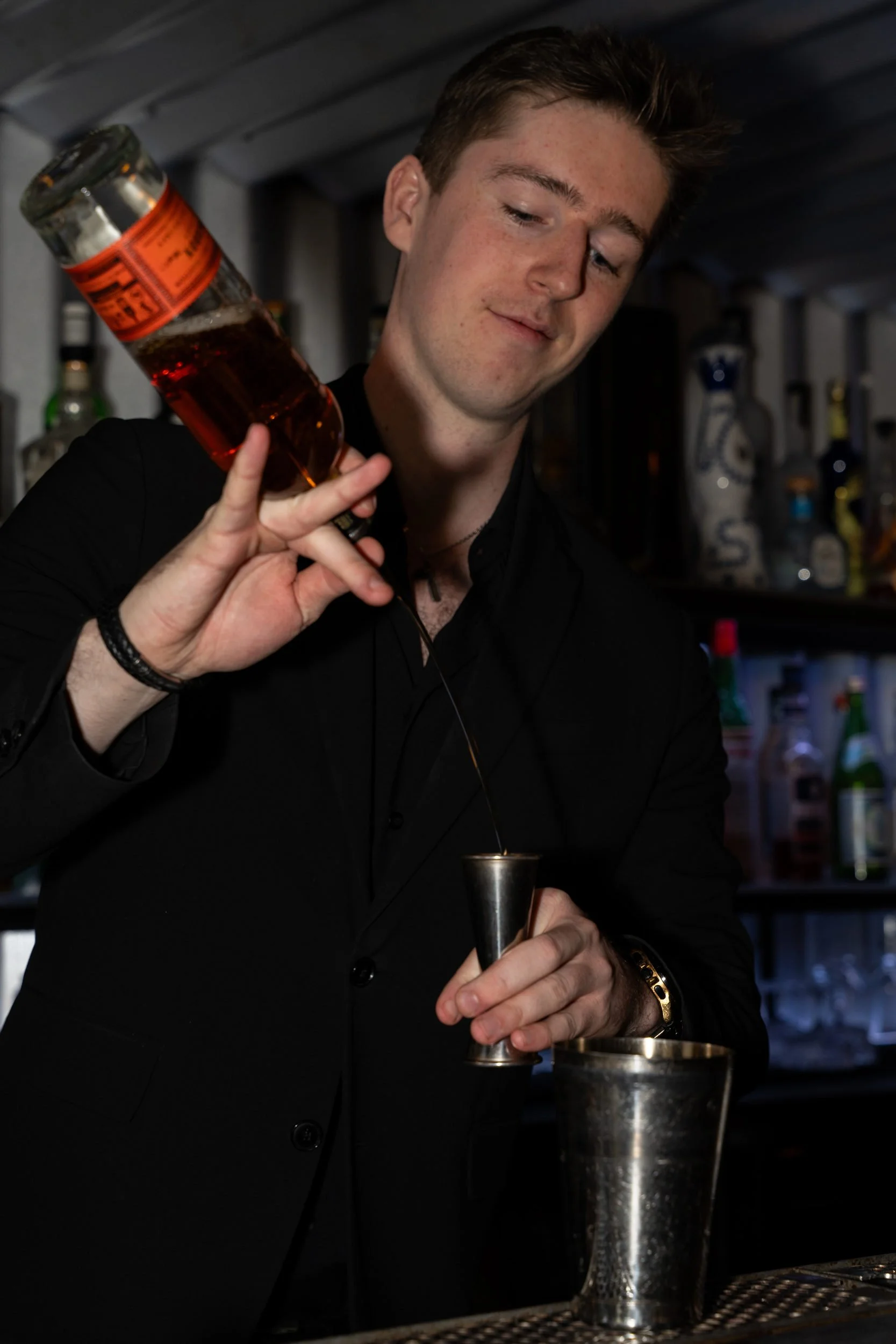 Bartender hælder fra en flaske i målebægeret på Little Green Door København