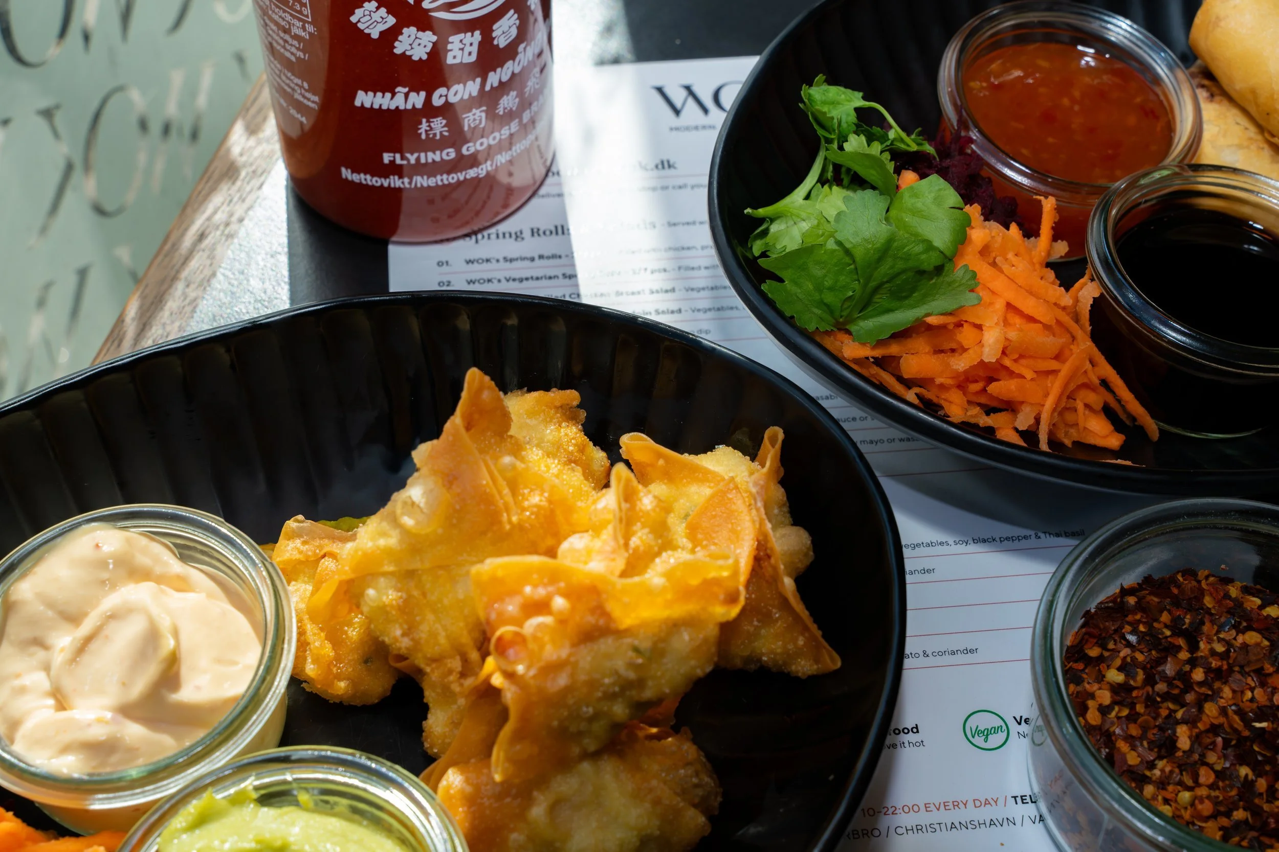 Table spread of crispy Thai starters with dipping sauces and fresh garnish at WOK Copenhagen – food photography by Monday's Photo