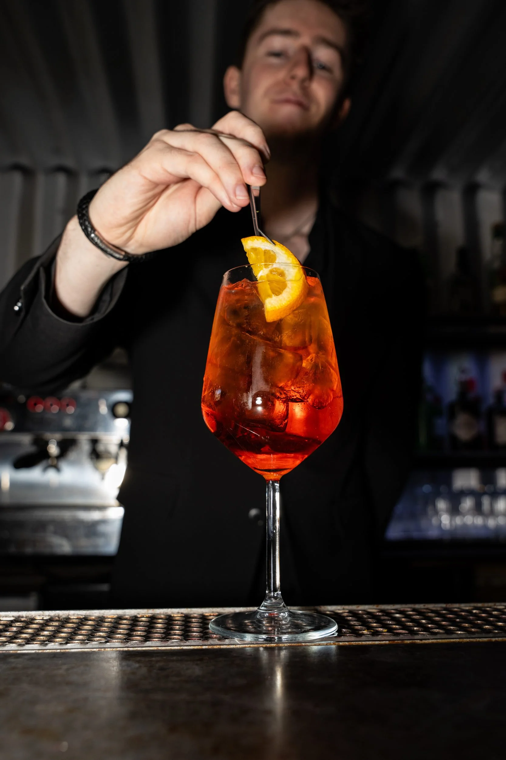 Bartender pynter en orange spritz med en appelsinskive på Little Green Door København