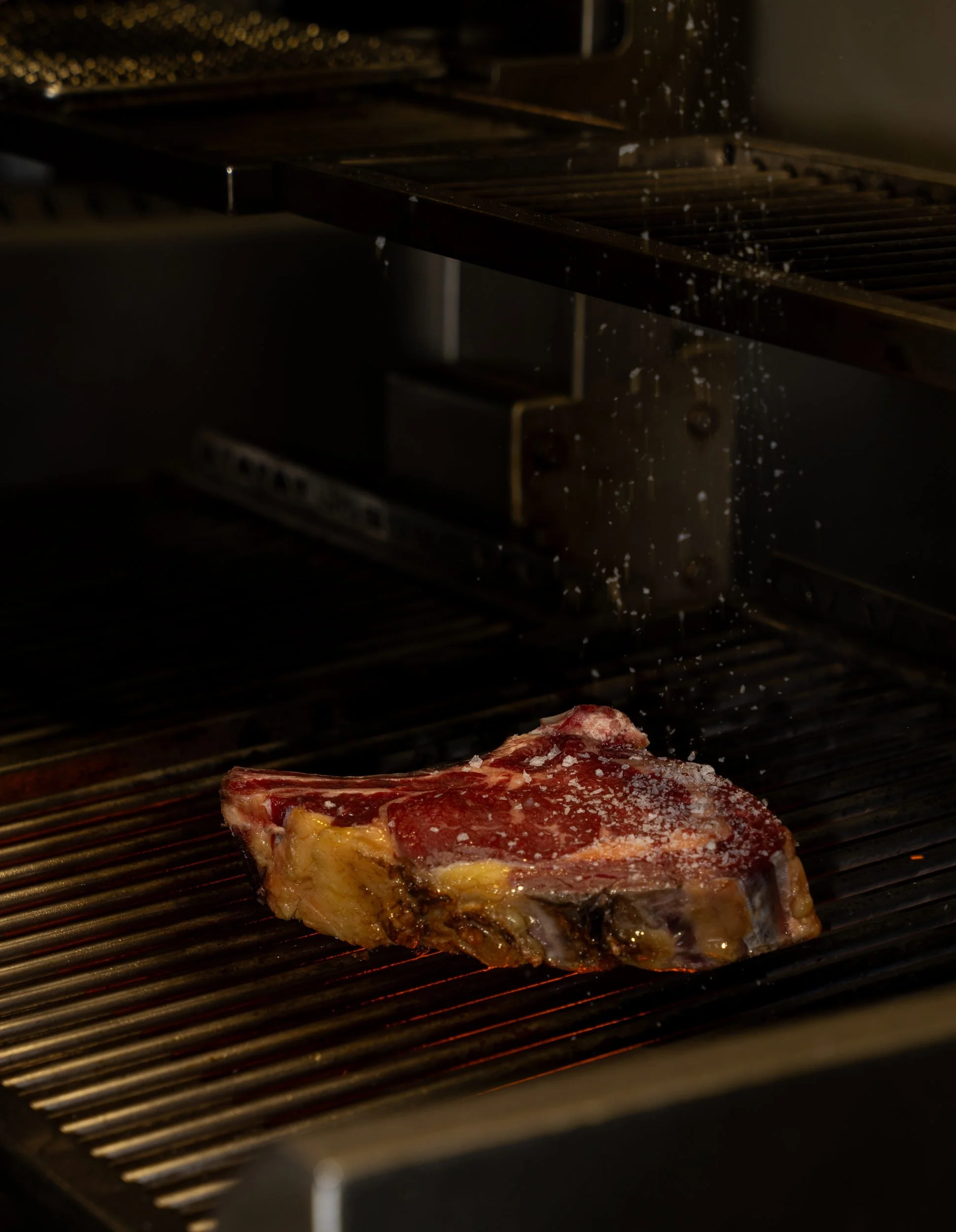 Salt drysses over en bøf med ben på grillristen hos A Hereford Beefstouw