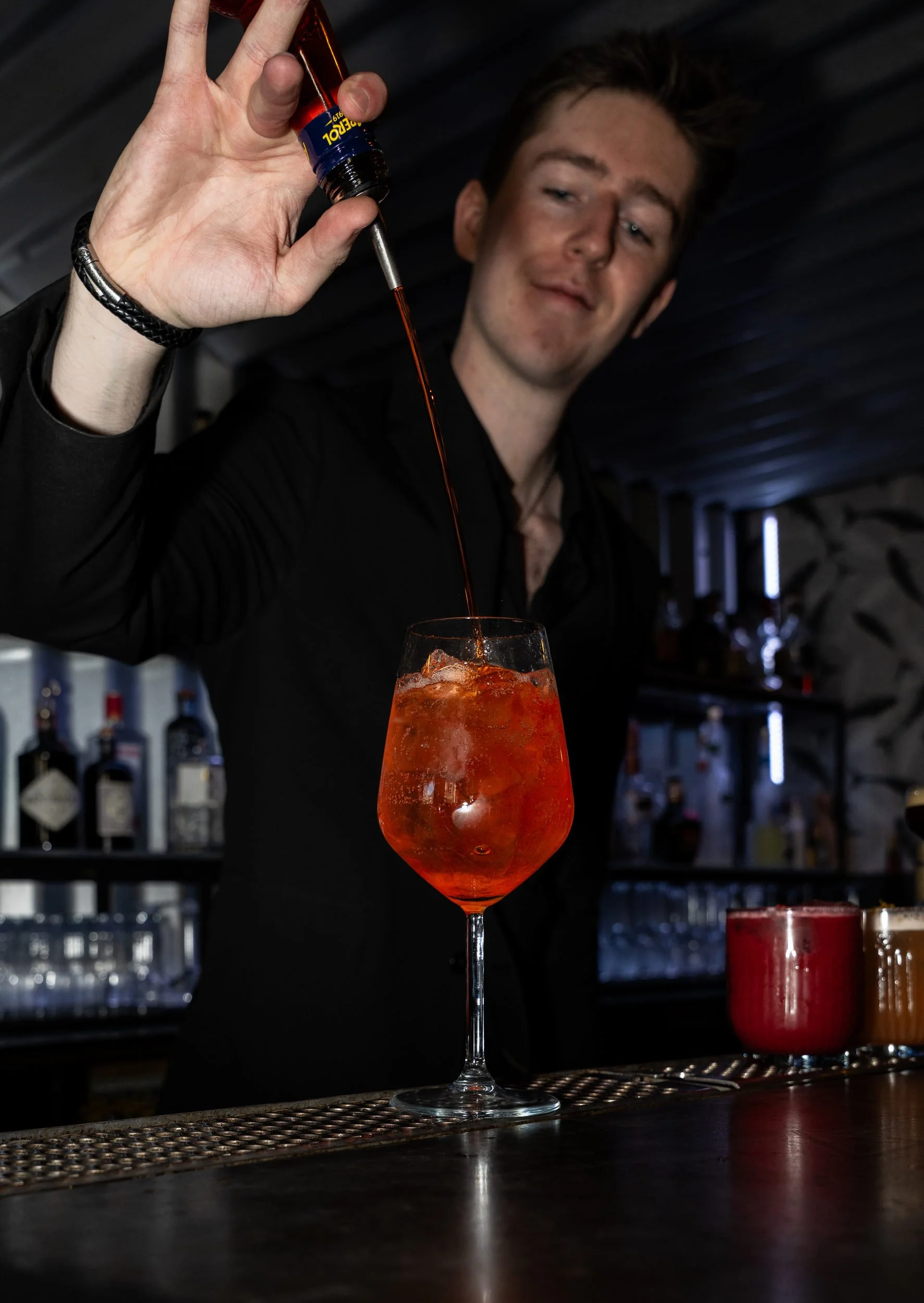 Bartender hælder i et vinglas med orange spritz og is på Little Green Door København