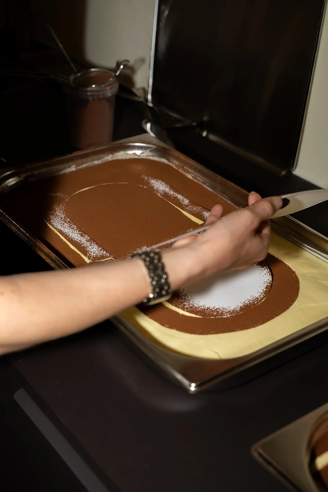 Kakaomønster lægges på tiramisu med en skabelon før eventet hos Arturel