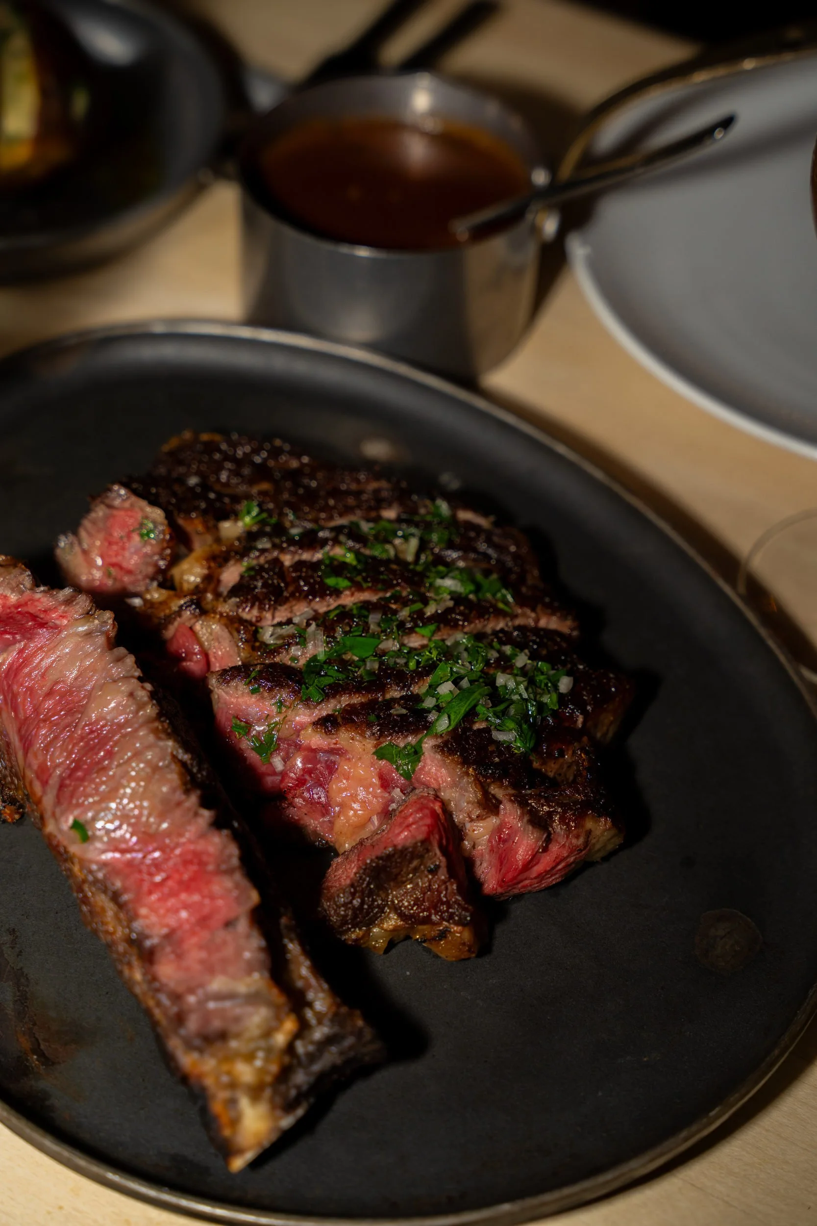 Skåret rosa bøf med hakkede krydderurter på sort fad hos A Hereford Beefstouw