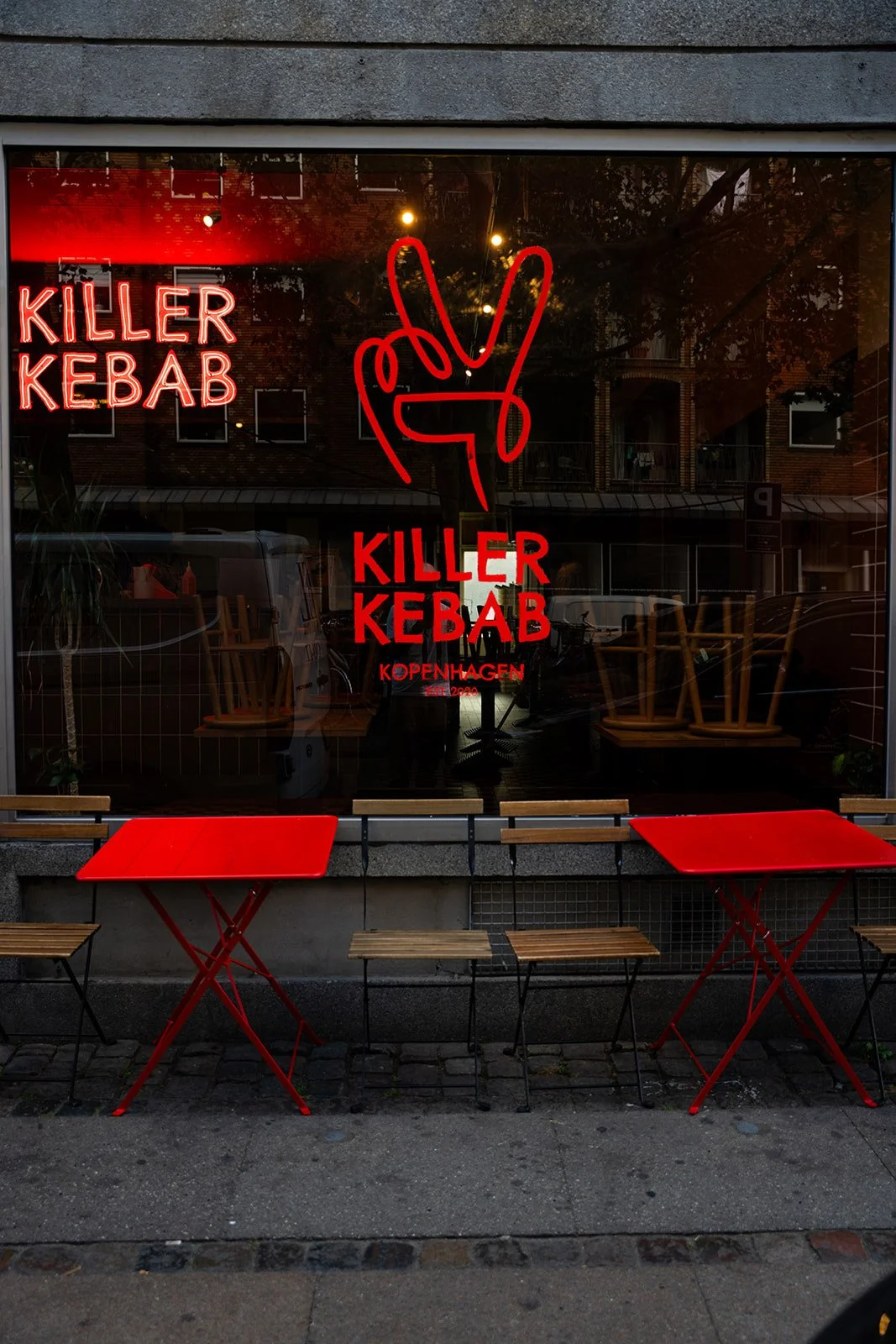 Killer Kebabs facade med rødt neonlogo i vinduet og røde borde udenfor
