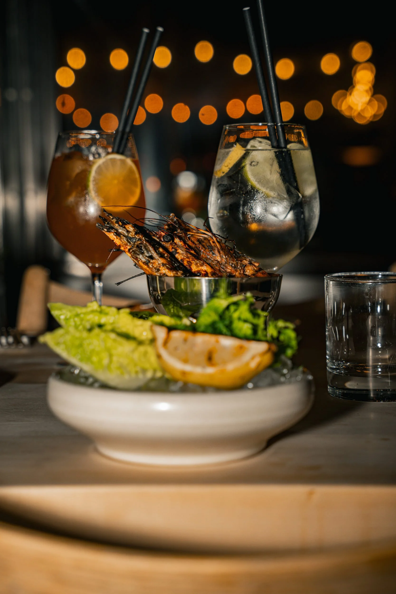 Rejer og salat med citron i en skål foran cocktails i baren hos A Hereford Beefstouw