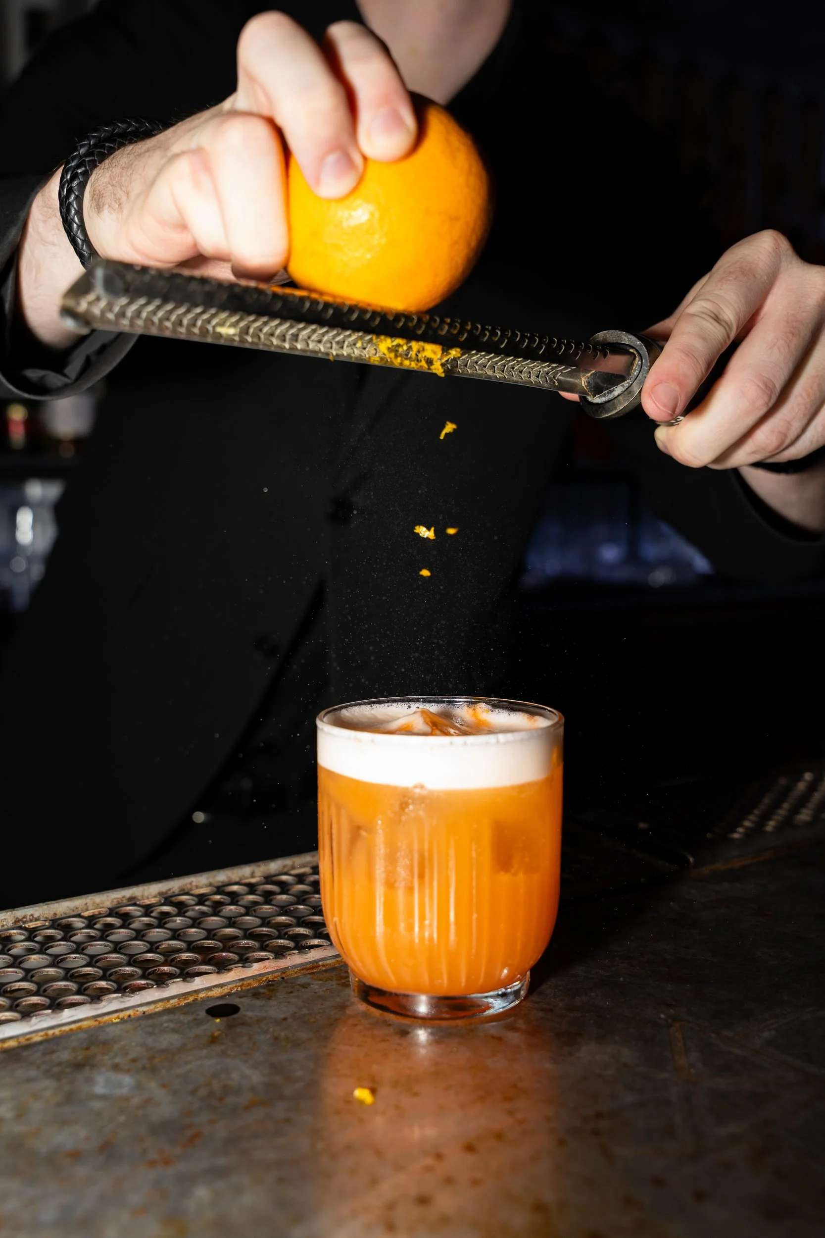 Appelsinskal rives over en skummende cocktail på baren hos Little Green Door