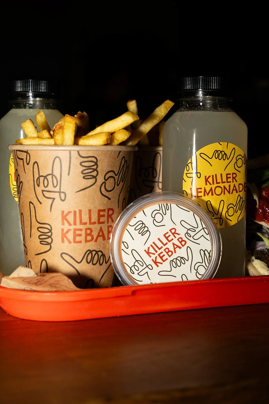 Pommes frites og to flasker lemonade på en rød bakke med Killer Kebab-emballage