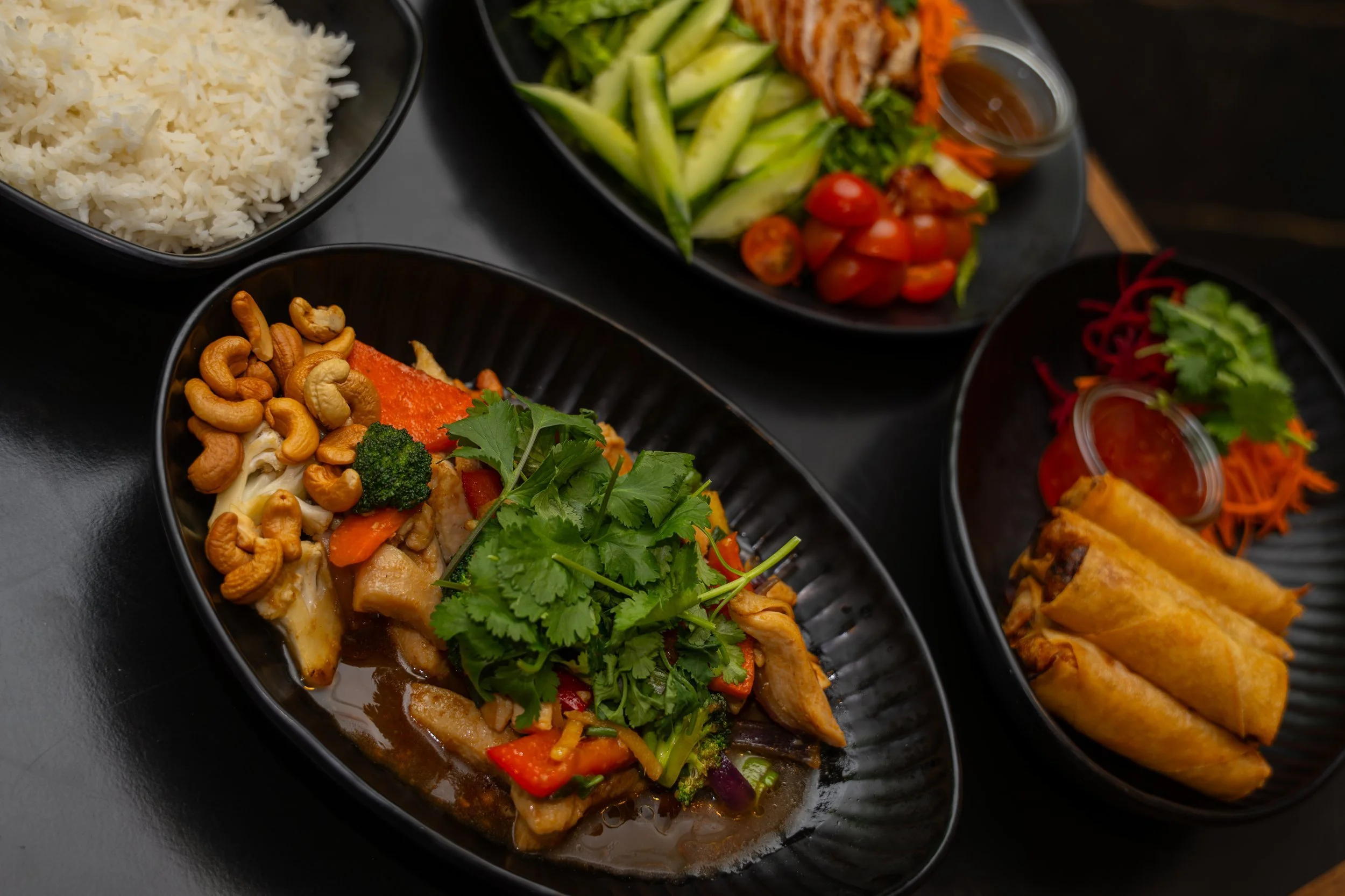 Overhead shot of cashew stir-fry with herbs and crispy spring rolls at WOK Copenhagen