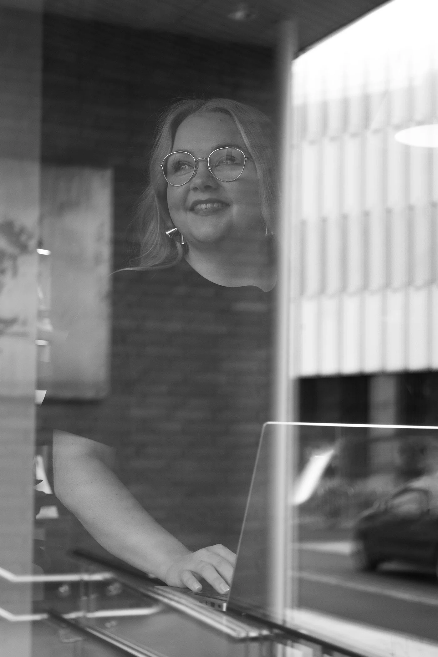 Sanna Perälä vetämässä Luova strateginen ajattelu -työpajaa – näkymä ikkunan läpi koneella työskentelevästä strategia-asiantuntijasta