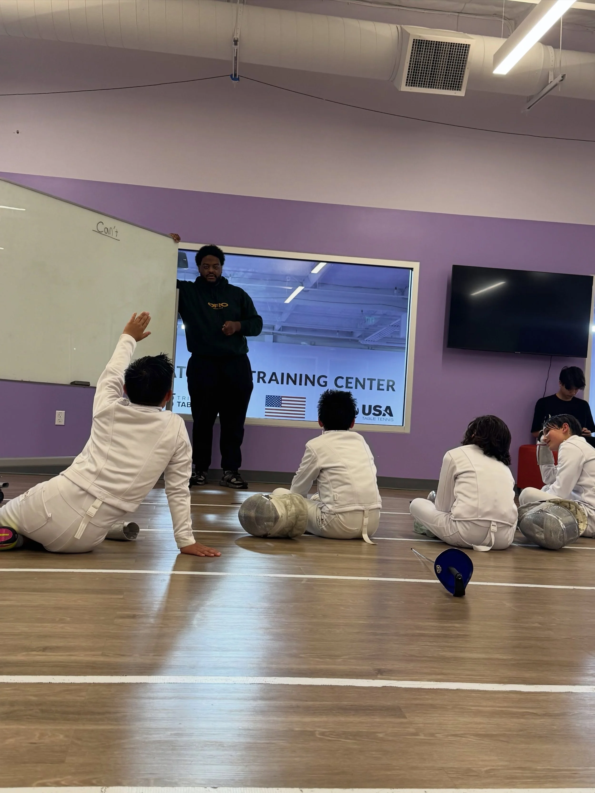 Coach Justin breaking down the tactical game with the squad. Fencing is physical chess, and mastering the strip starts with mastering the strategy off it. 📈