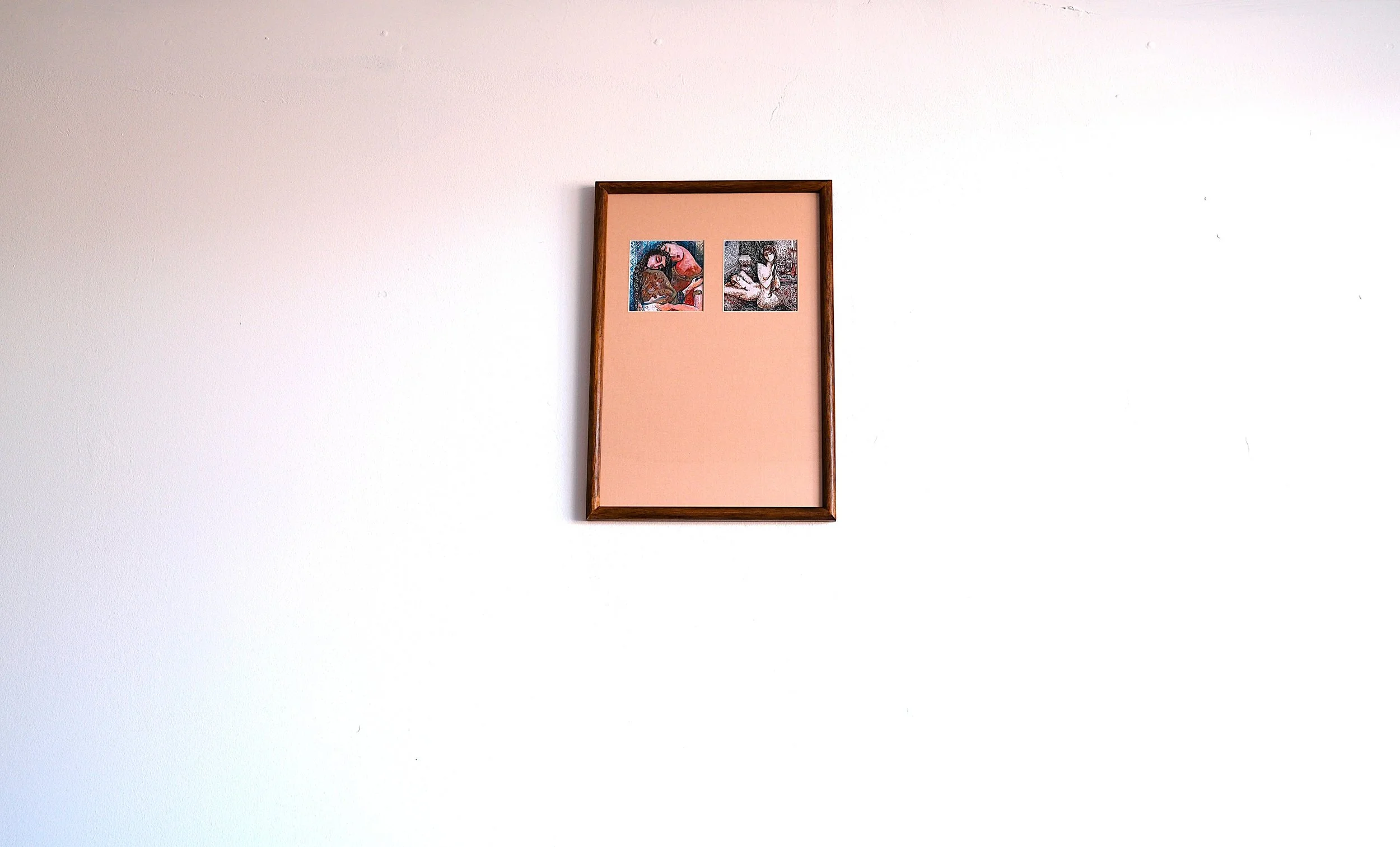 A framed picture on a white wall with two small images, one in color and one in black and white, placed in a pink background space.