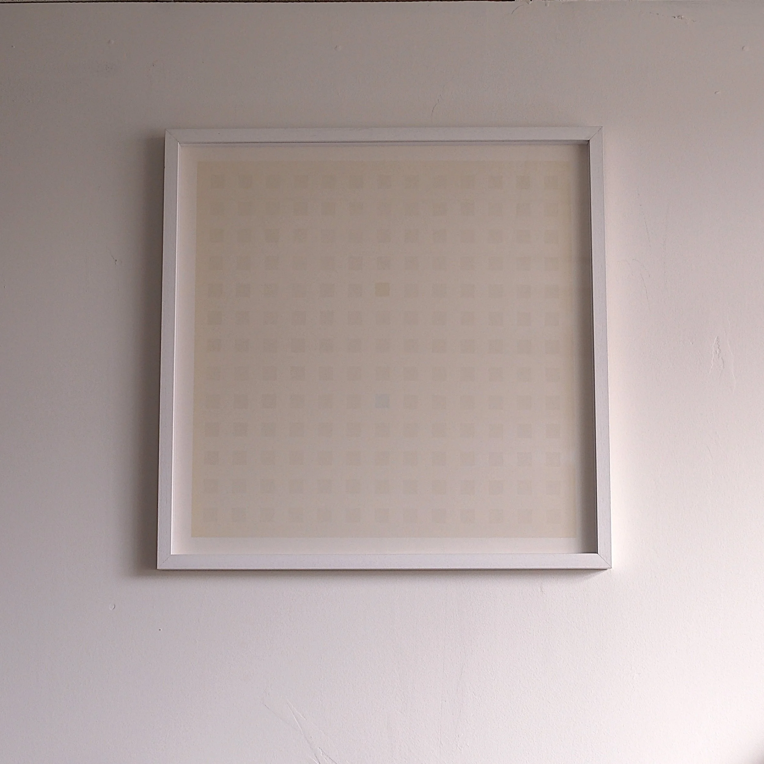 Empty white picture frame hanging on a white wall