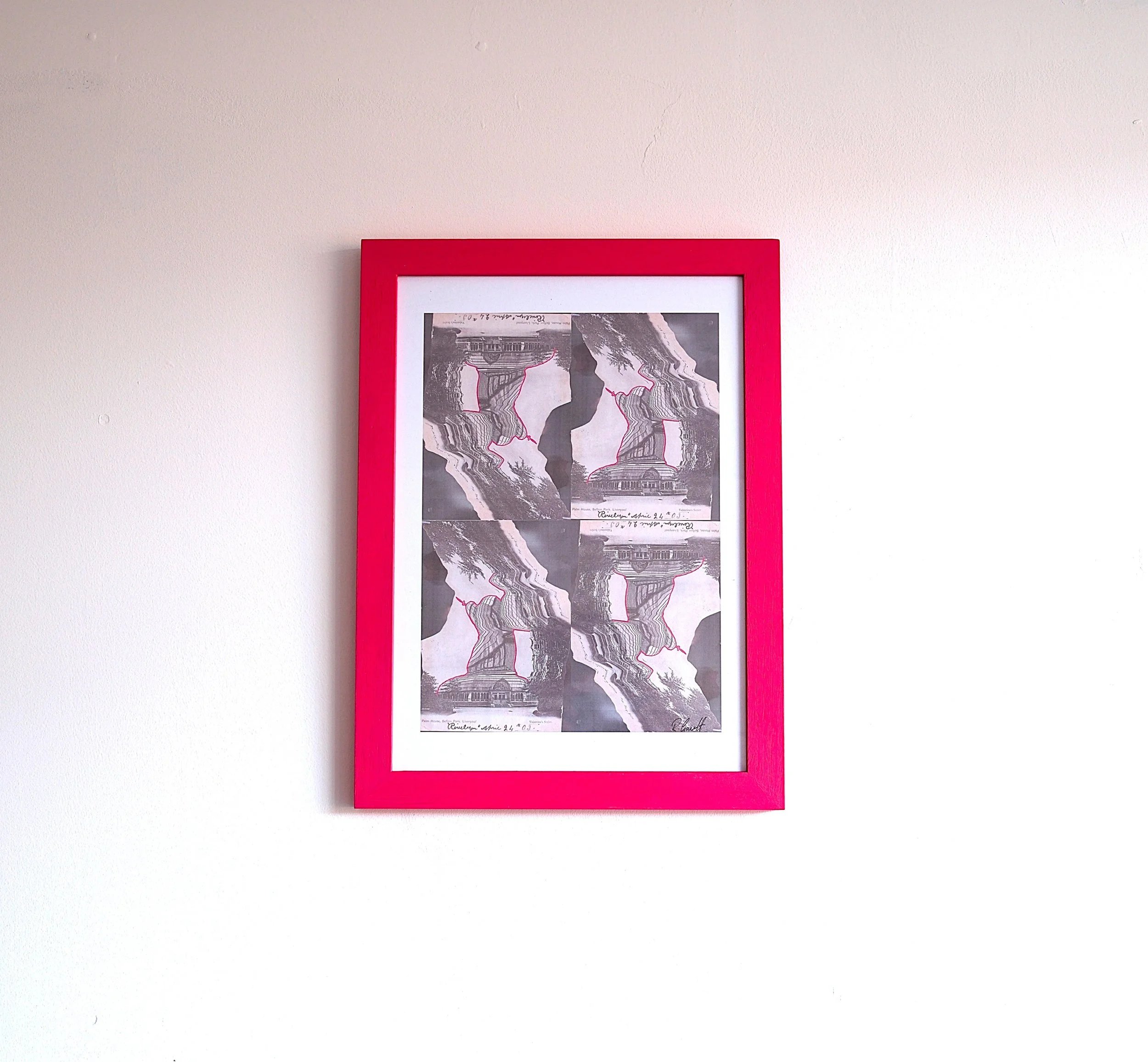 Framed black-and-white artwork of a landscape with trees and buildings, mounted on a white wall.