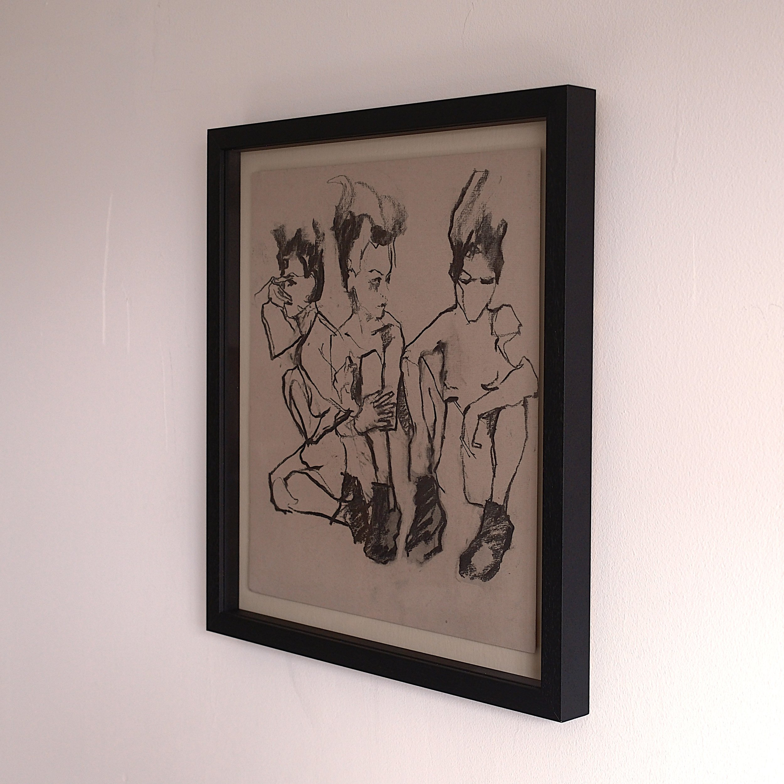 A framed monochrome sketch of three women sitting together, some with hands on their laps or using a phone, with abstract hair and facial features.