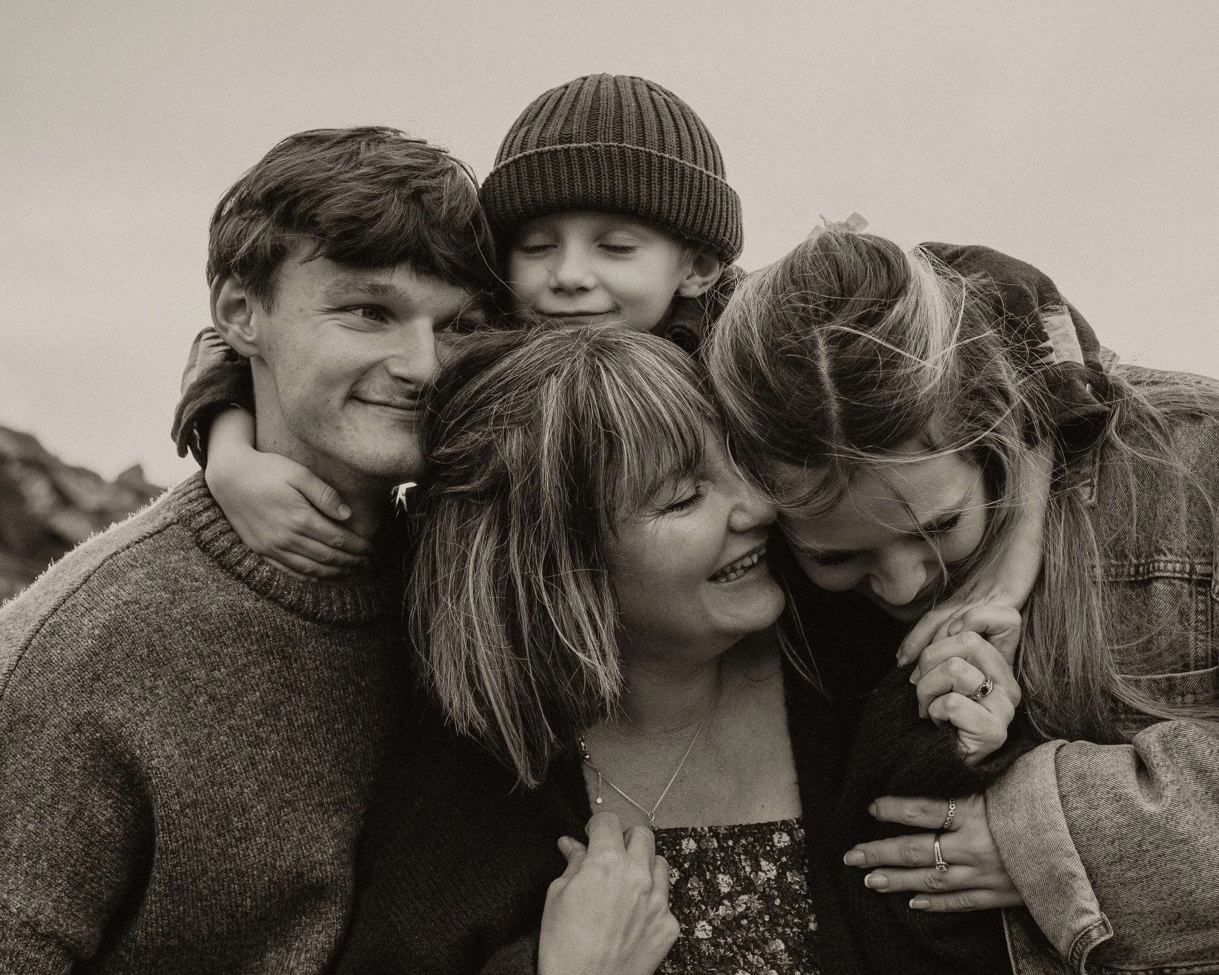 Mother with her children embracing outdoors in Cornwall, natural family photography capturing motherhood and connection