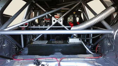 Interior of a race car showing roll cage, racing seats, and electronic equipment